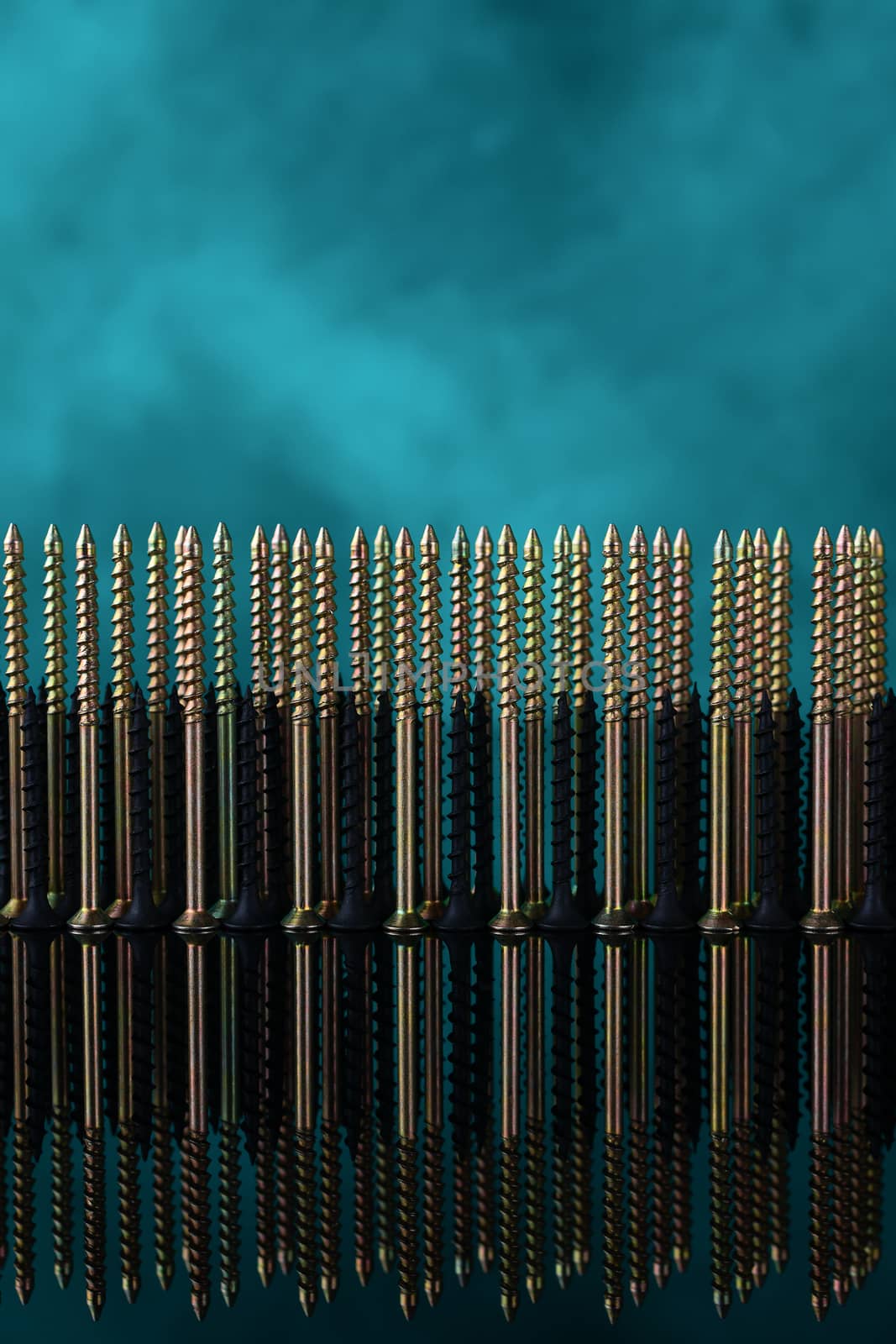 Screws and dowels on glass on turquoise background. Symbol of team work, invincibility and power of team army. Creative photo of screws and dowels.