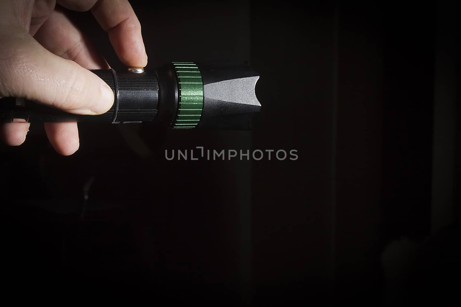 Male hand holds a black metal flashlight