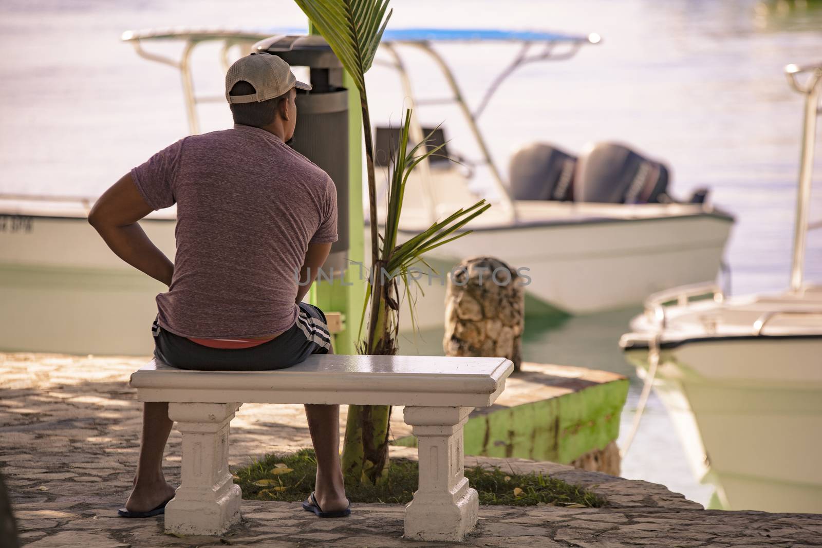 Man sitting on the bench looks at the sea from the port of Bayahibe in Dominican Republic