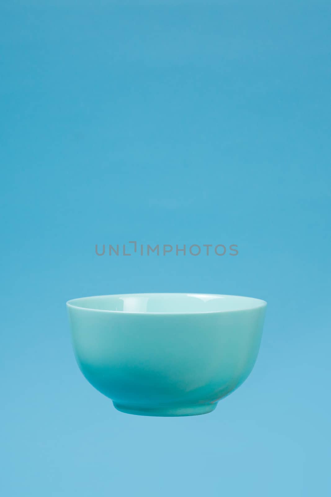 A blue ceramic mattle deep bowl for breakfast flying on blue background. Ideal photo for levitation of food and fruits or nuts.