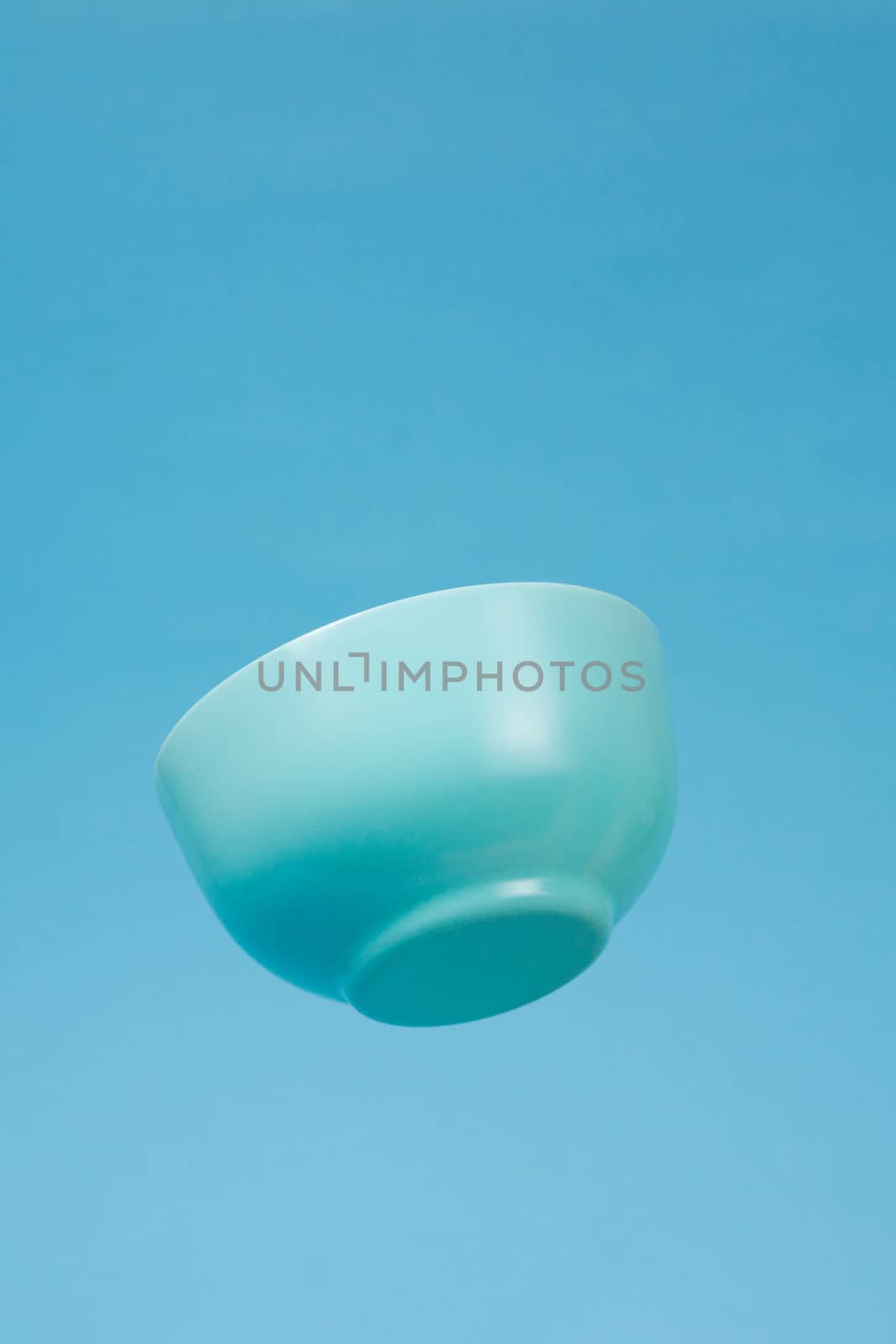 A blue ceramic mattle deep bowl for breakfast flying on blue background. Ideal photo for levitation of food and fruits or nuts.