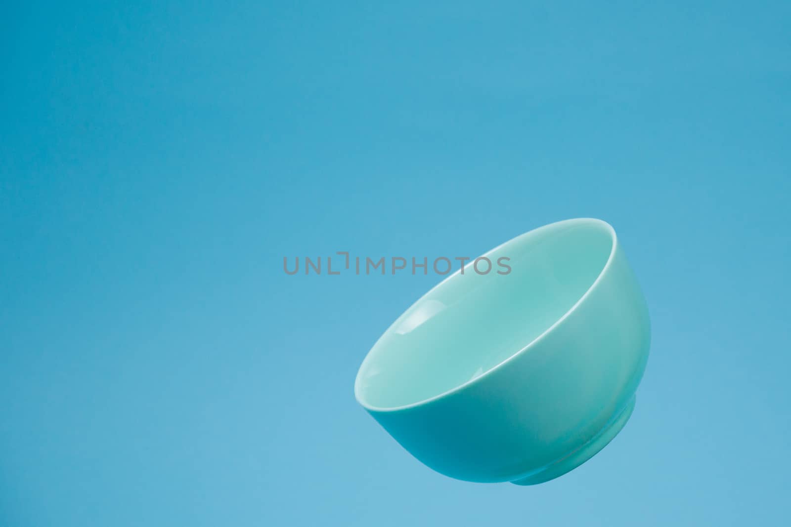 A blue ceramic mattle deep bowl for breakfast flying on blue bac by alexsdriver