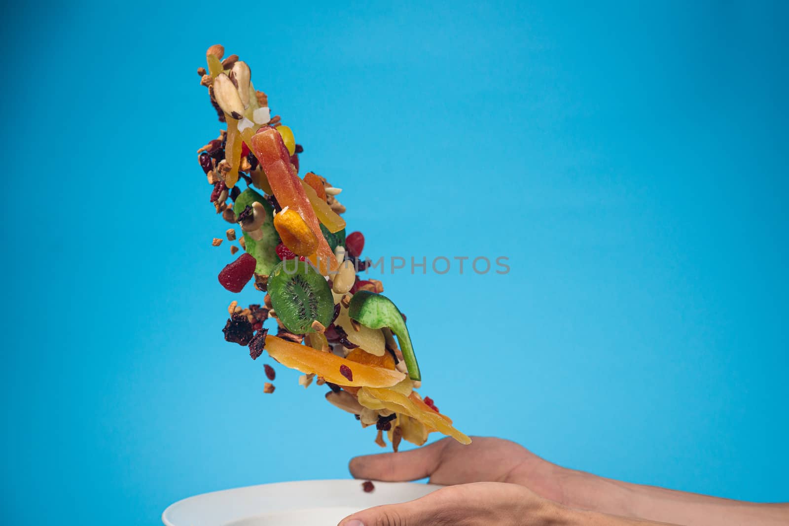 Male hands holding an empty white bowl on blue background. Candi by alexsdriver