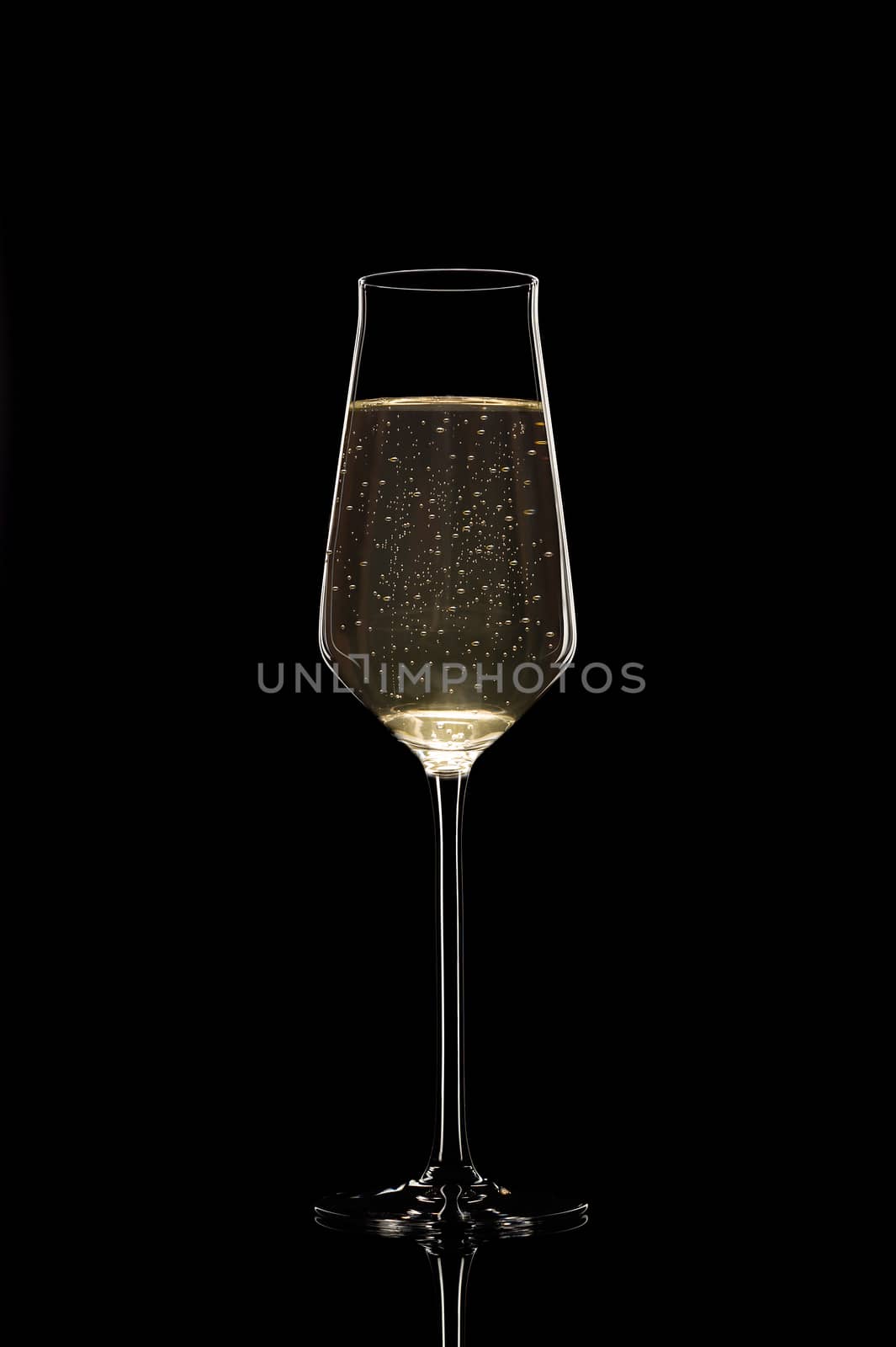 An unusual thin filled champagne glass with bubbles isolated on  by alexsdriver