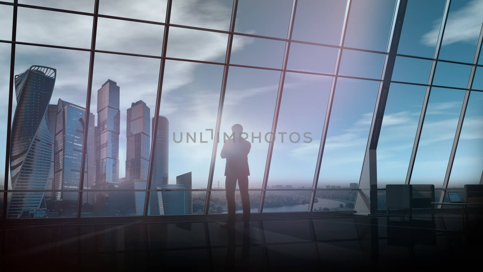 A silhouette of a businessman is looking out of the window of his large office against the backdrop of skyscrapers.