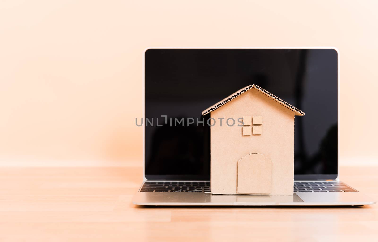 Cardboard paper model house and computer laptop, property mortgage rent buy concept