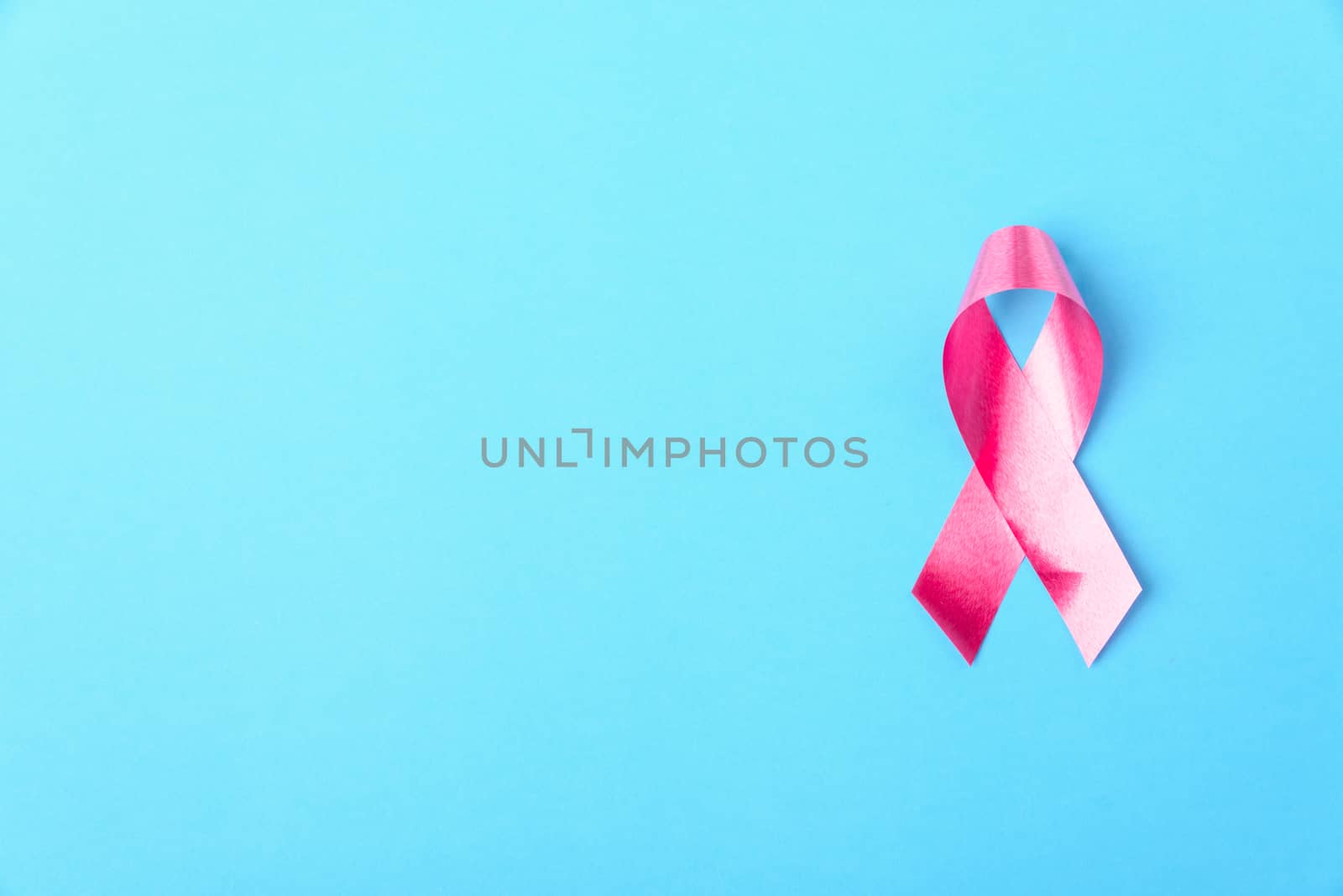 Breast cancer month concept, flat lay top view, pink ribbon on blue background with copy space for your text