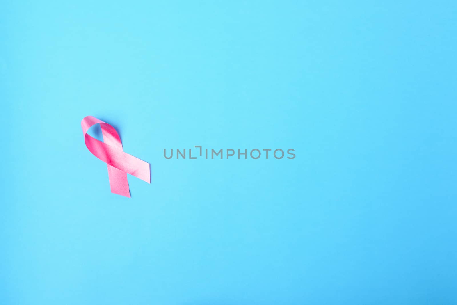 Breast cancer month concept, flat lay top view, pink ribbon on blue background with copy space for your text