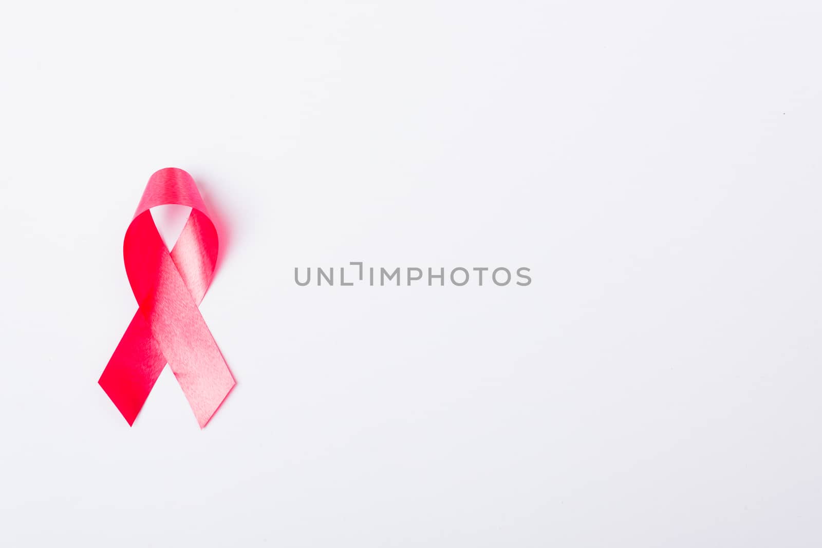 Breast cancer month concept, flat lay top view, pink ribbon on white background with copy space for your text