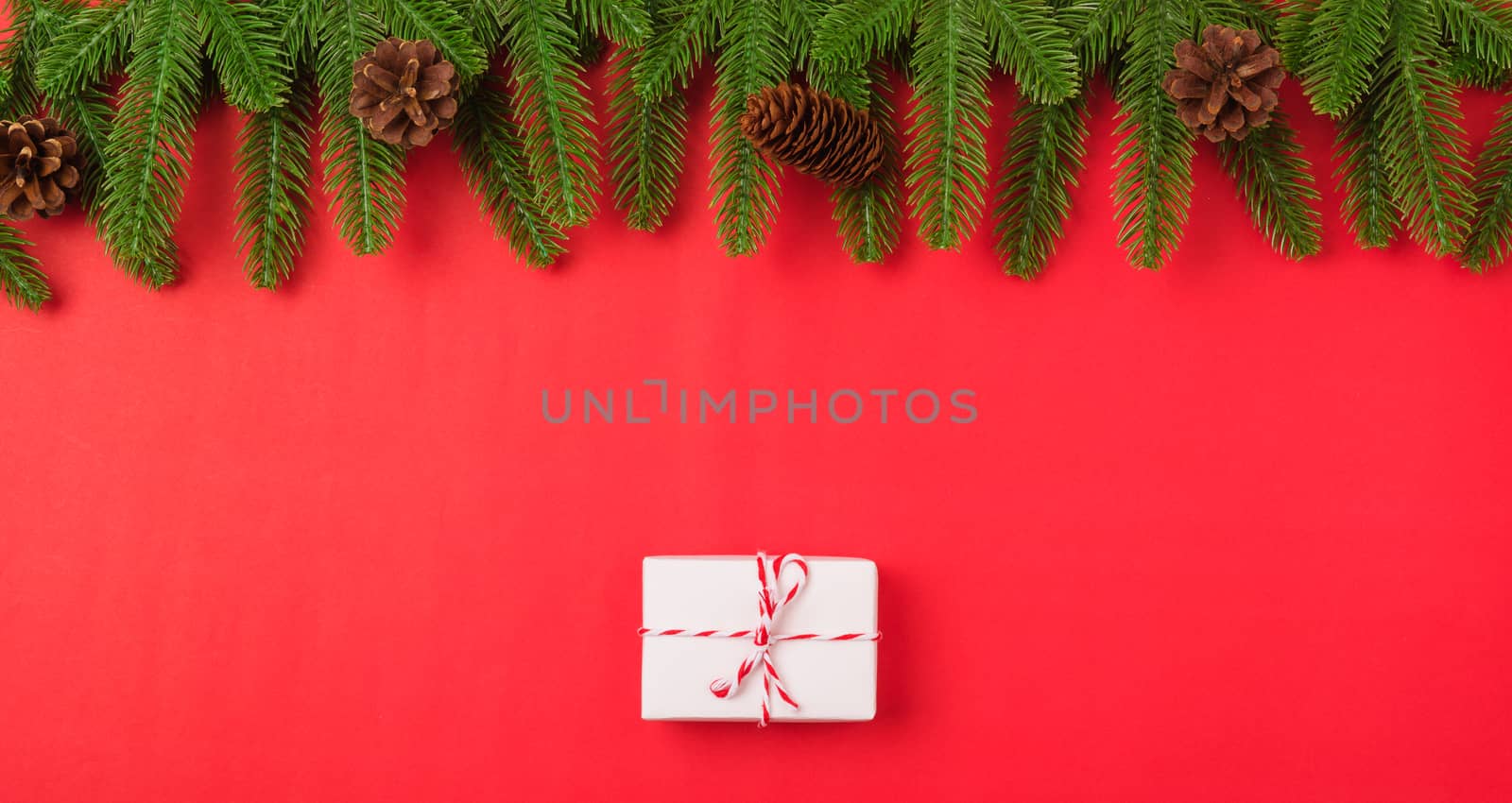 Happy new year or christmas day top view flat lay fir tree branches and gift box, decoration on red background with copy space for your text