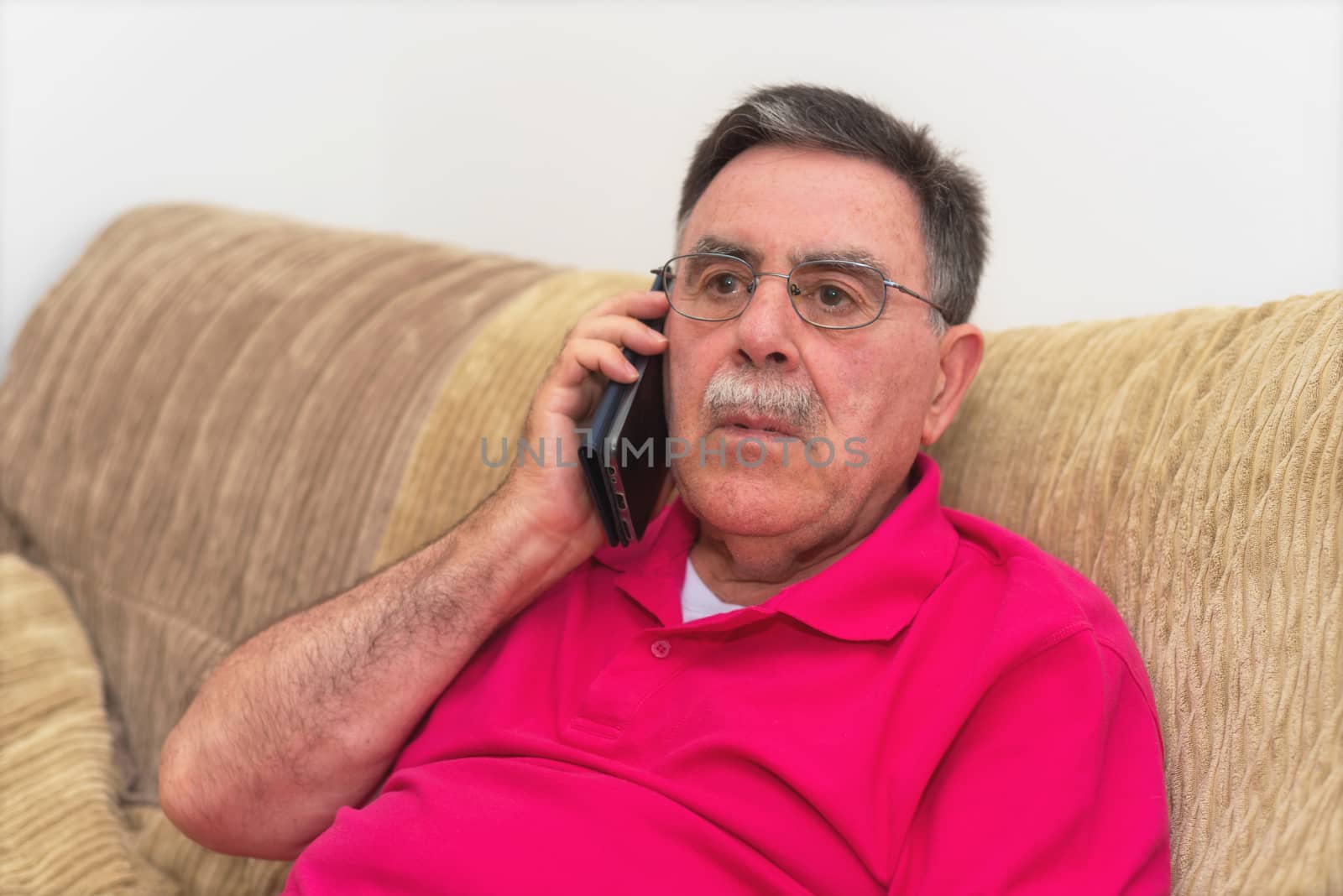 Portrait of a senior man serious expression talking on the phone by HERRAEZ