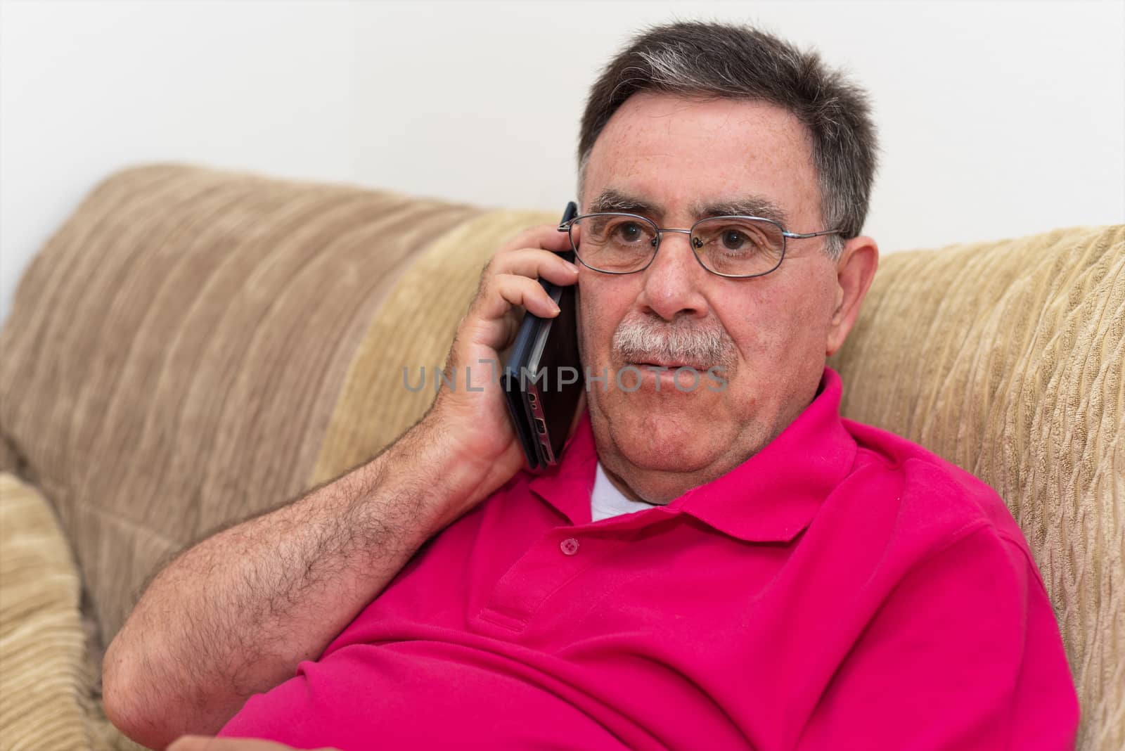 Portrait of a senior man serious expression talking on the phone by HERRAEZ