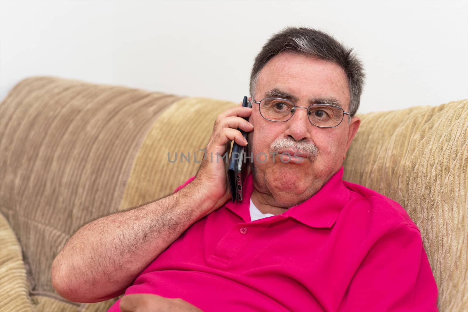 Portrait of a senior man serious expression talking on the phone by HERRAEZ