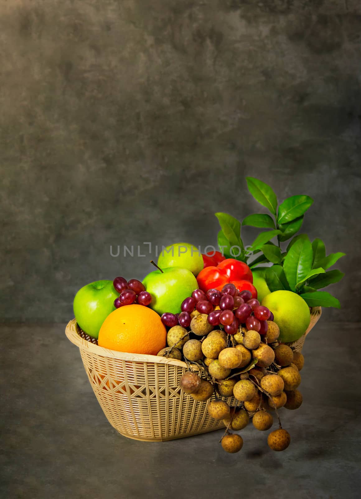 fresh vegetables and fruits in wicker basket over wooden background