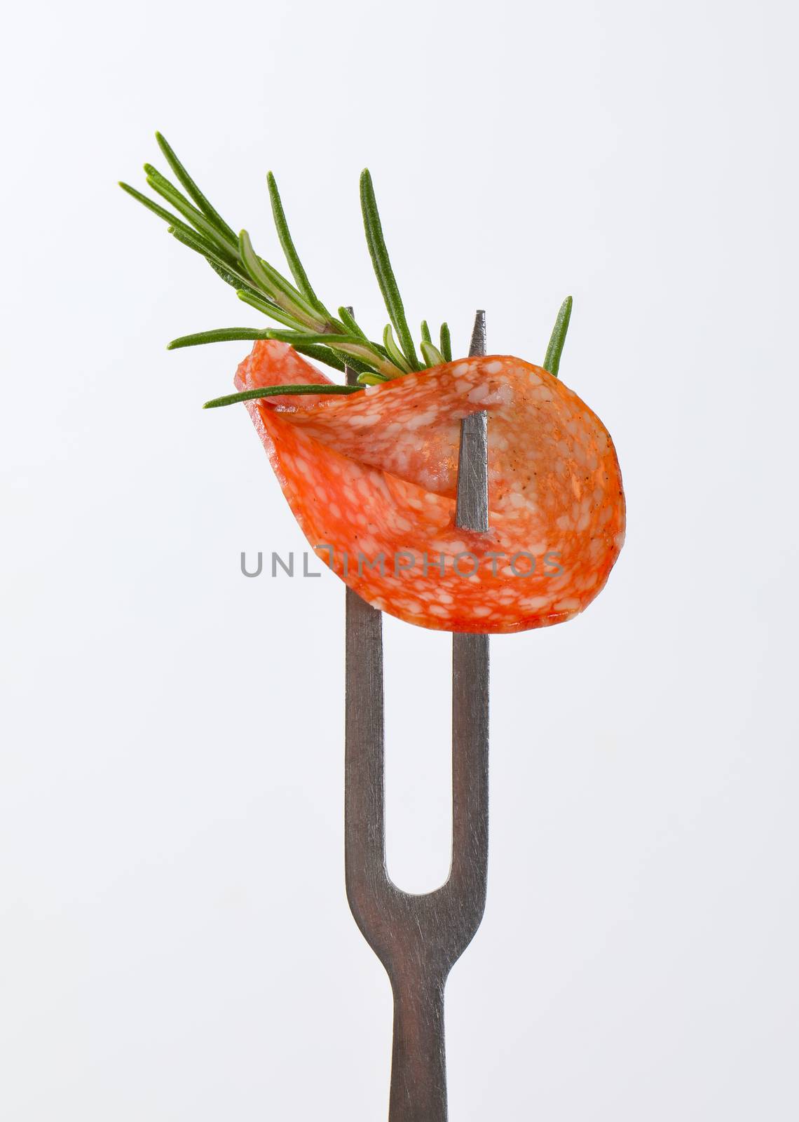 Slice of Hungarian salami and fresh rosemary on fork