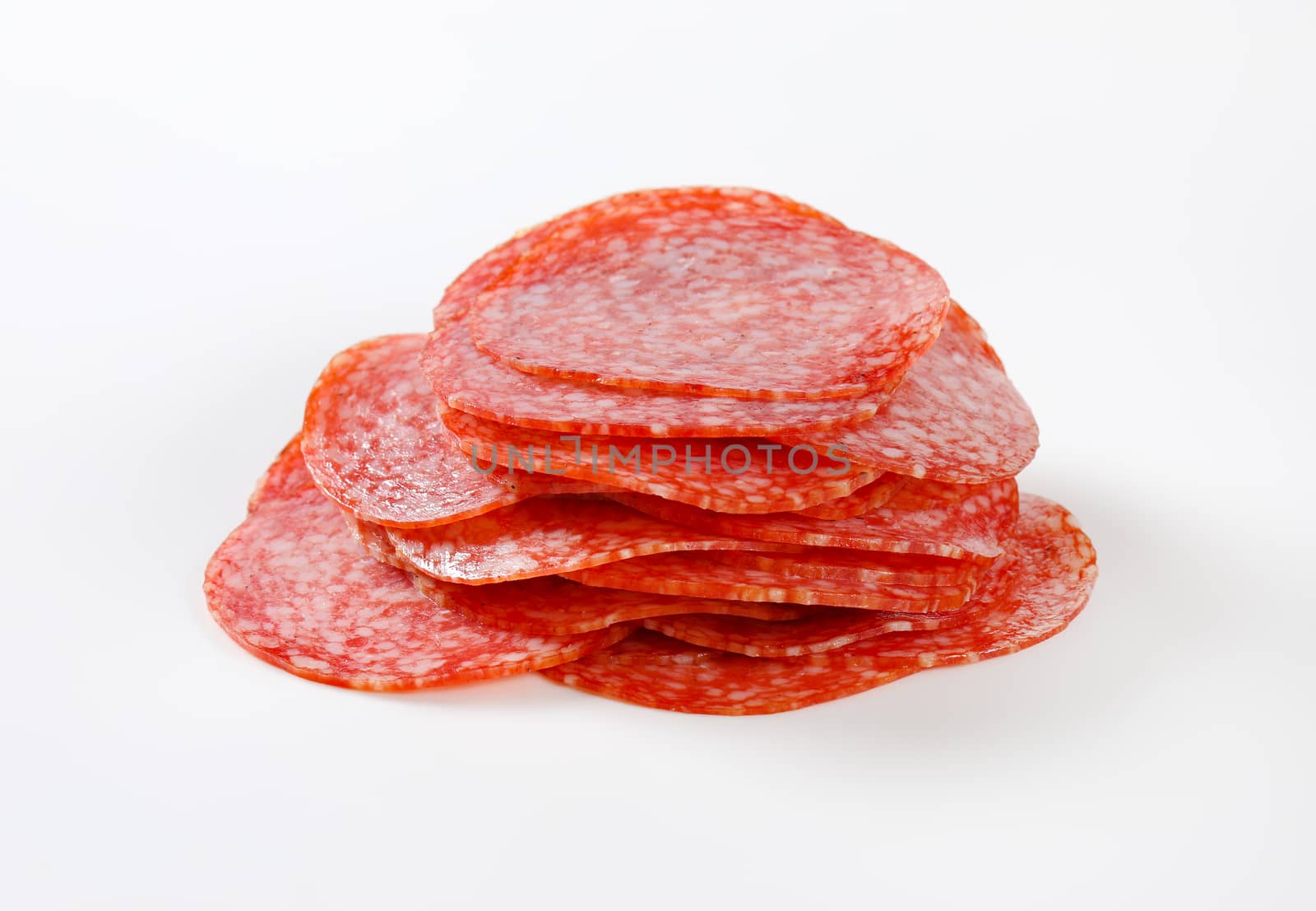 Thinly sliced salami sausage on white background
