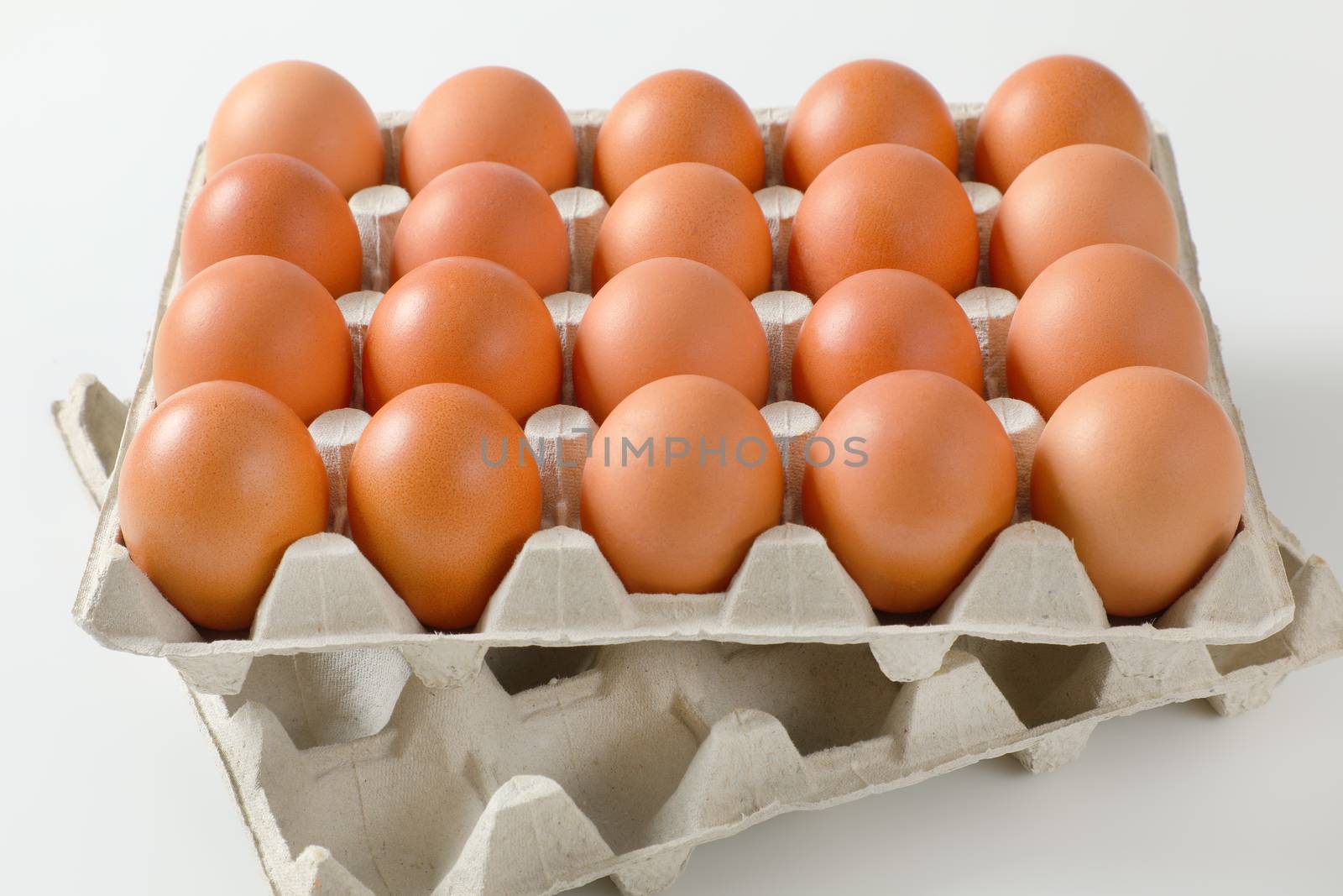 Twenty fresh brown eggs in a paper egg tray