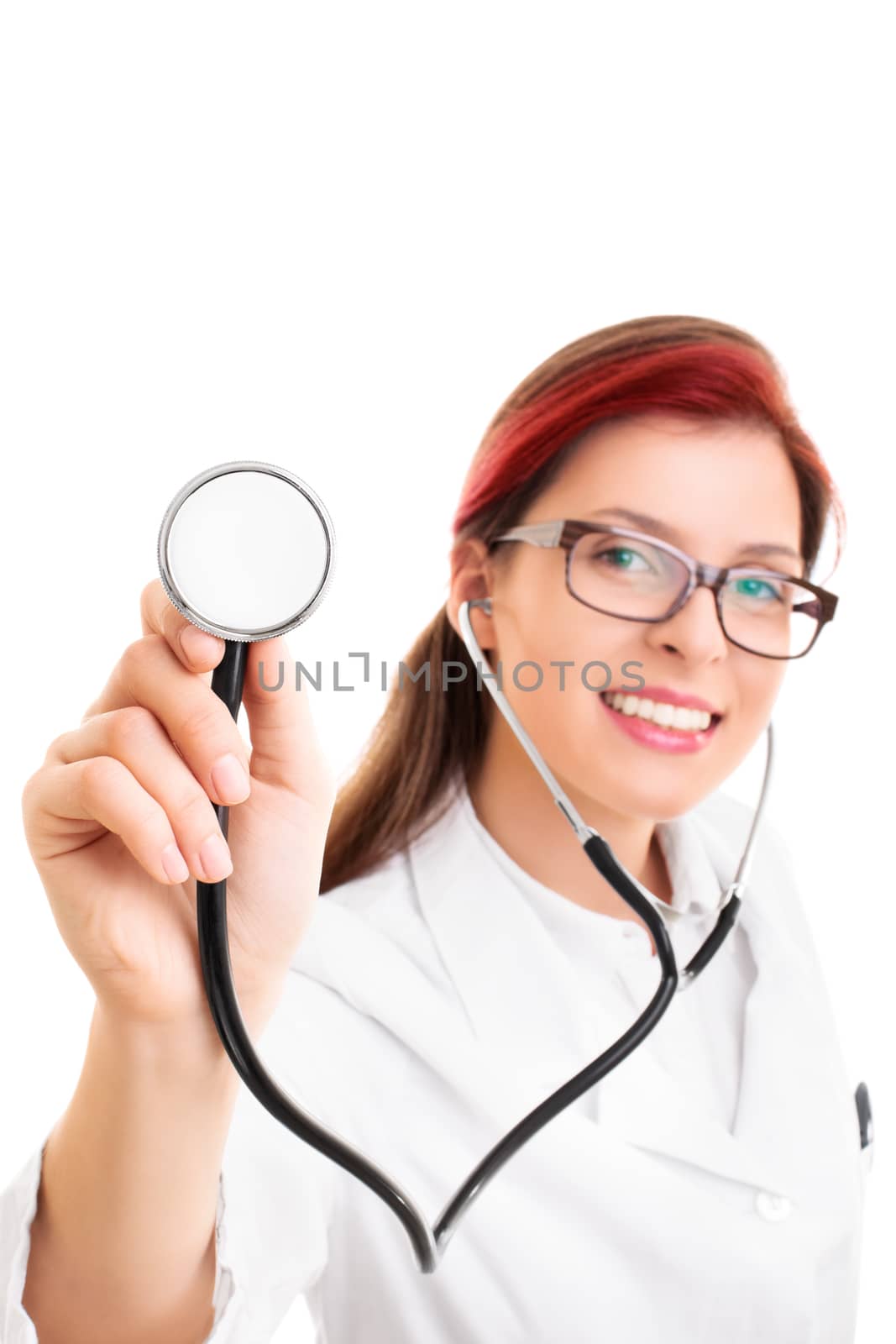 Portrait of a smiling young female health care professional or doctor or nurse with glasses holding stethoscope pointed toward camera, isolated on white background. Selective focus.