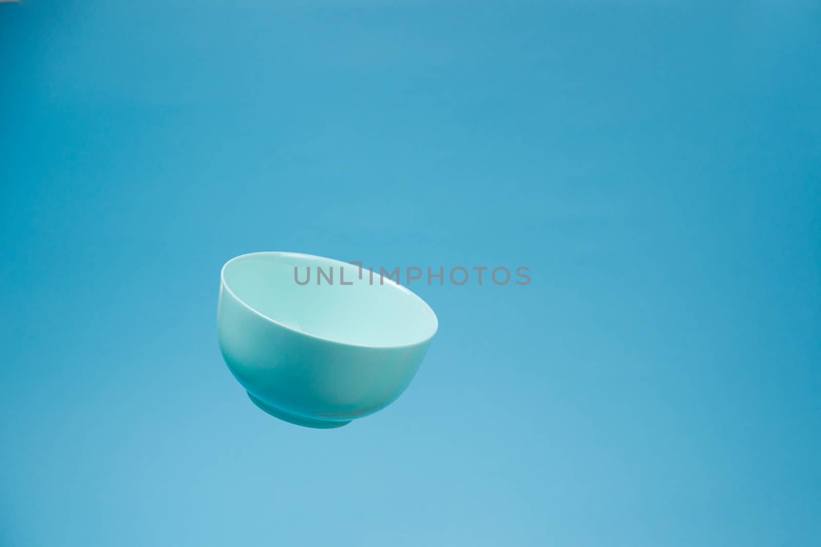 A blue ceramic mattle deep bowl for breakfast flying on blue bac by alexsdriver