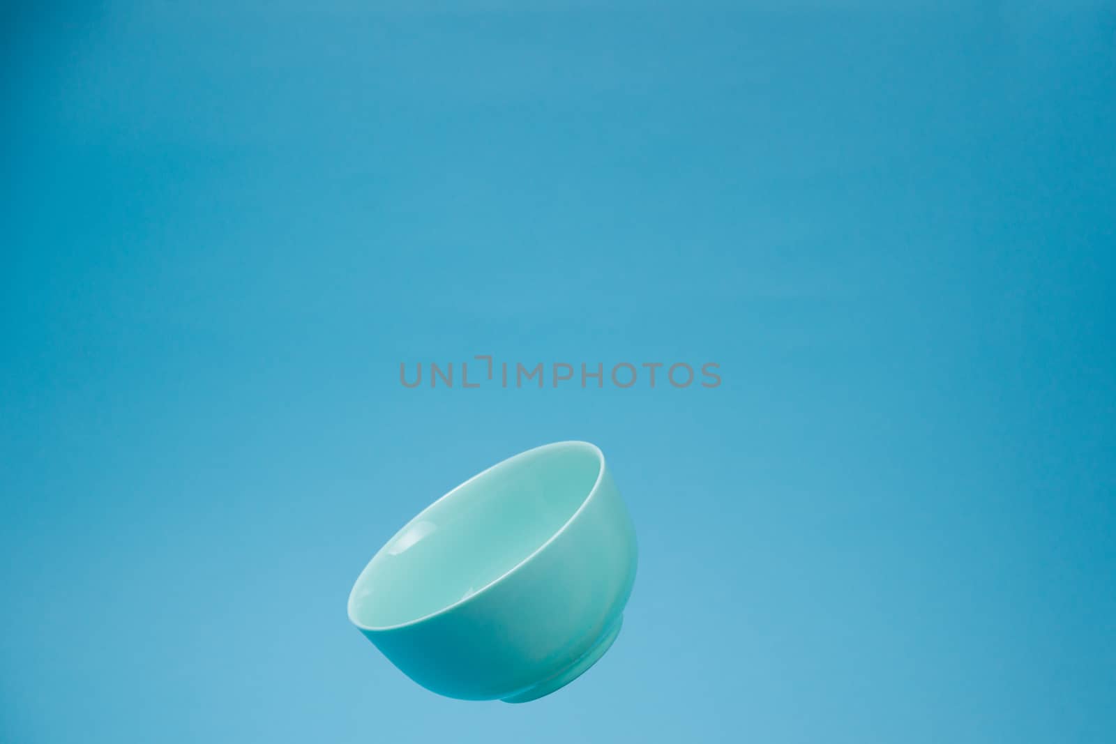 A blue ceramic mattle deep bowl for breakfast flying on blue background. Ideal photo for levitation of food and fruits or nuts.