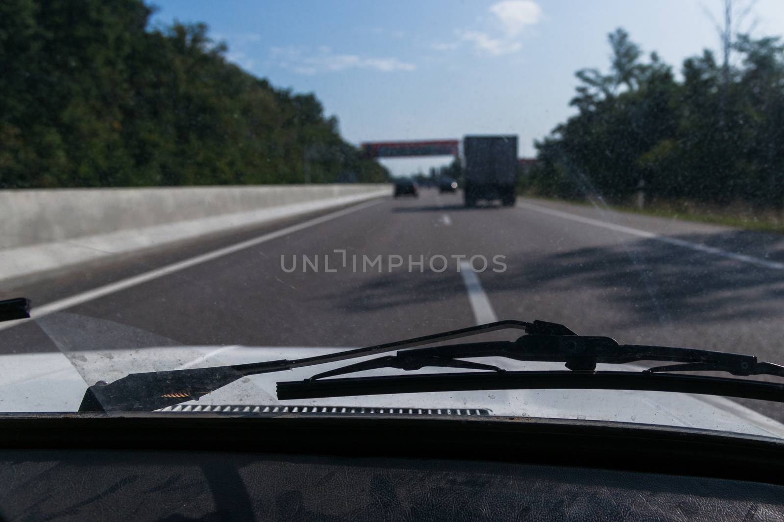 View of a passenger from the passenger compartment on the highway. A fine sunny day and almost free road. 