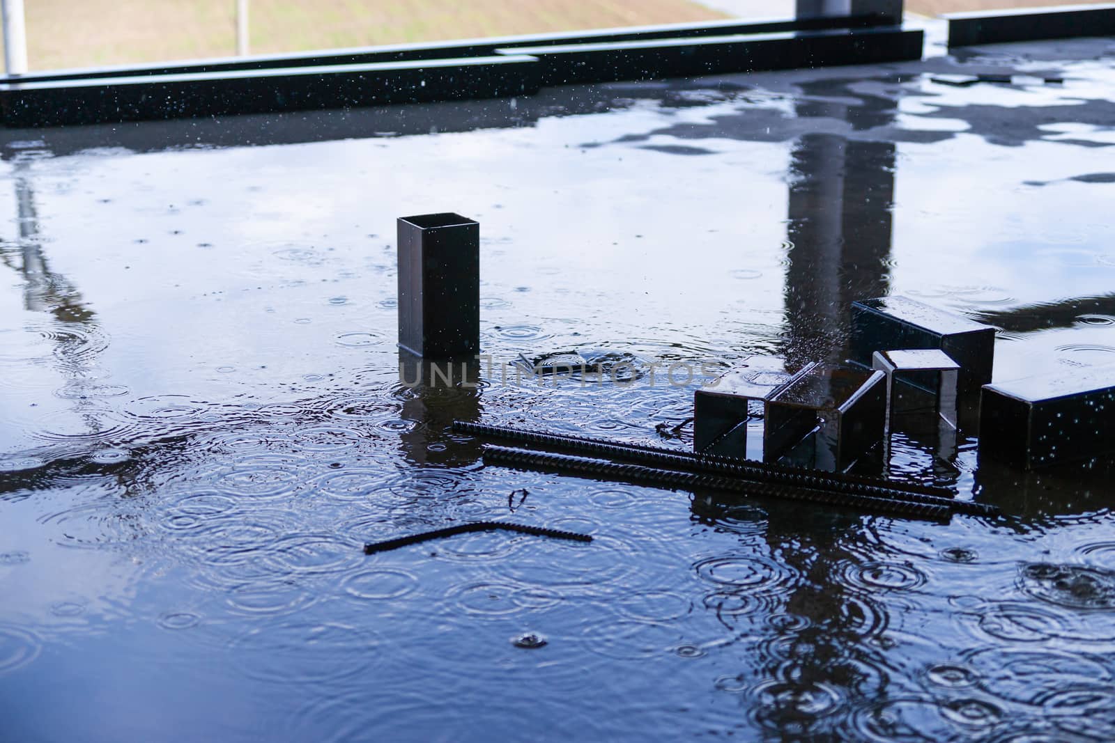 Rain drops and water on concrete with sky reflection in water