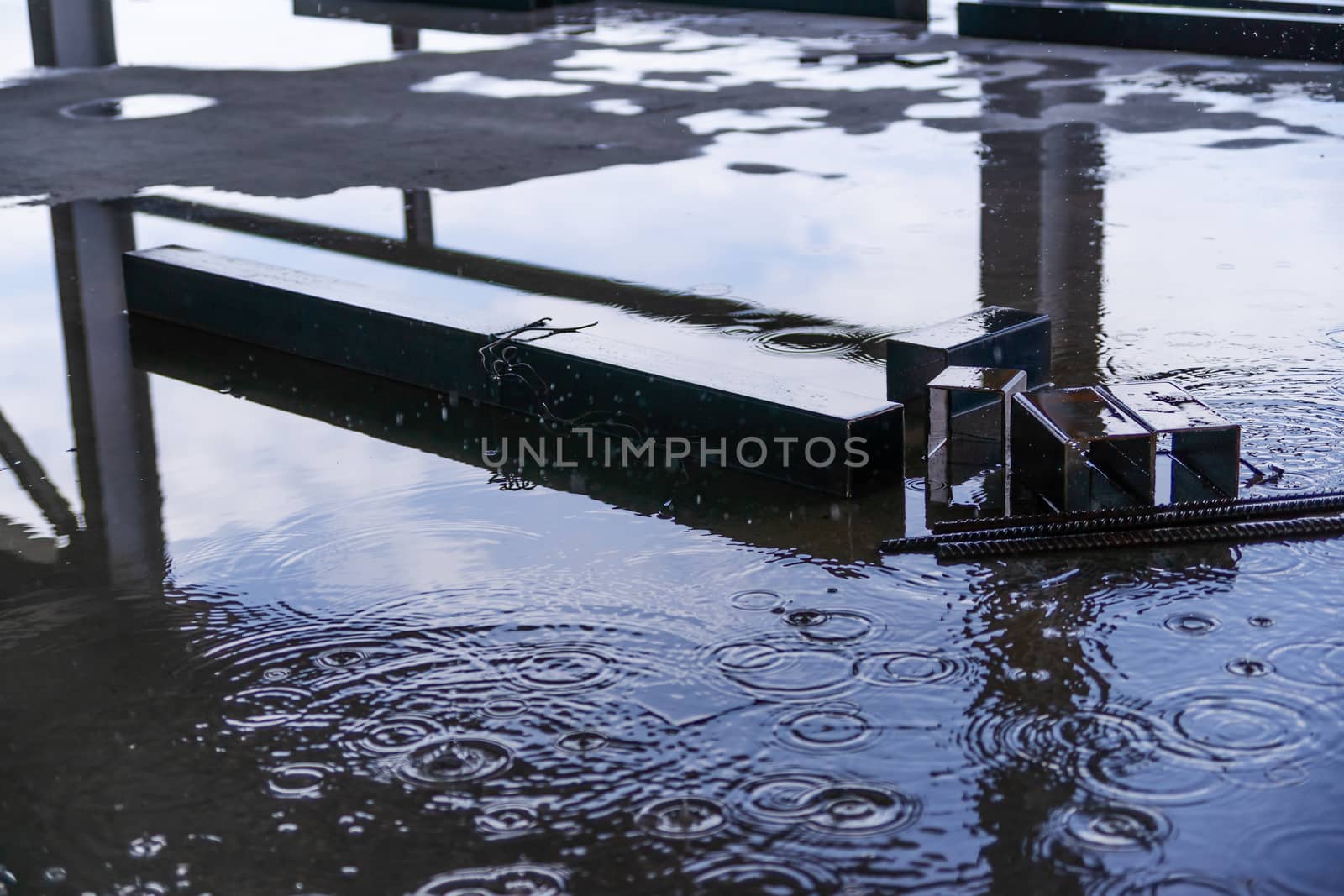 Rain drops and water on concrete with sky reflection in water