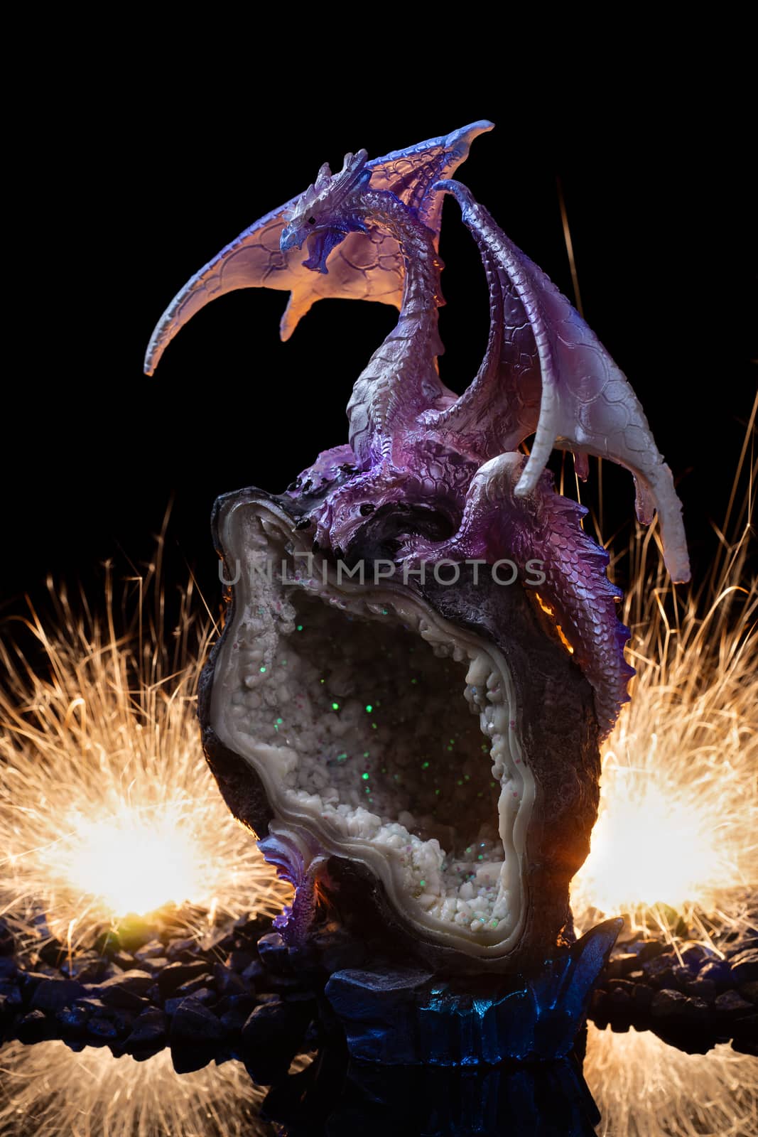 A ceramic statuette of white pink dragon on white-green stone with fire and sparks on background