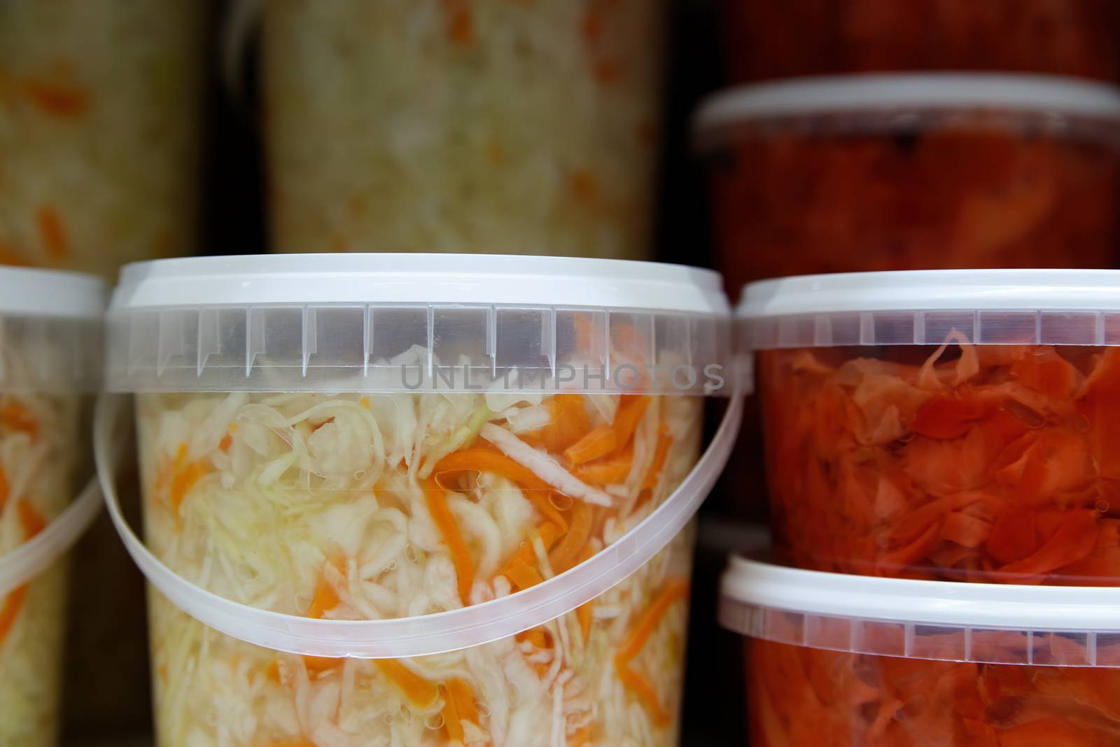Canned, marinated fermented and pickled vegetables in plastic jars. Sauerkraut, pickles, pickled ginger in the grocery store.