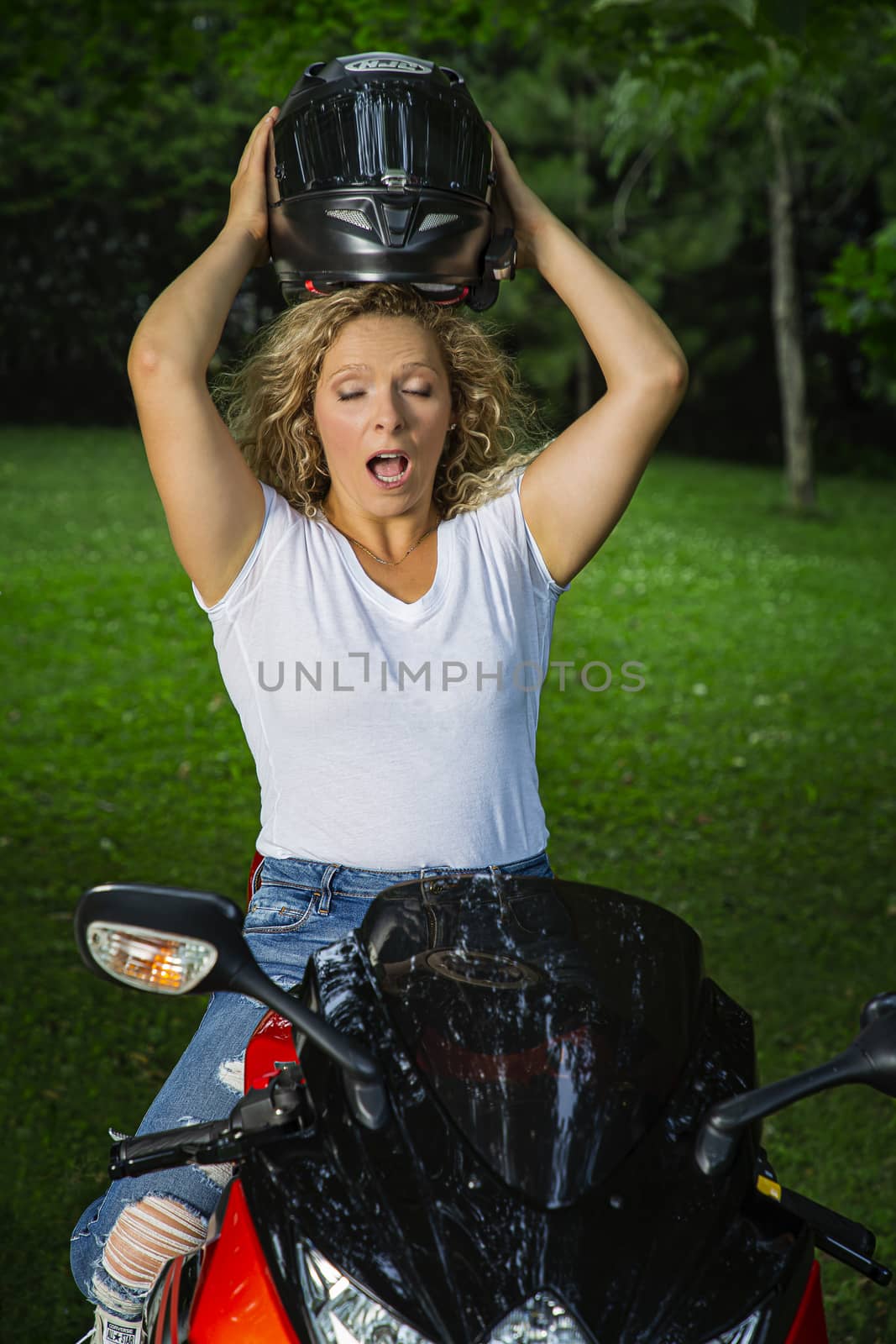 Woman trying to fit a sport motocycle helmet on top of her head