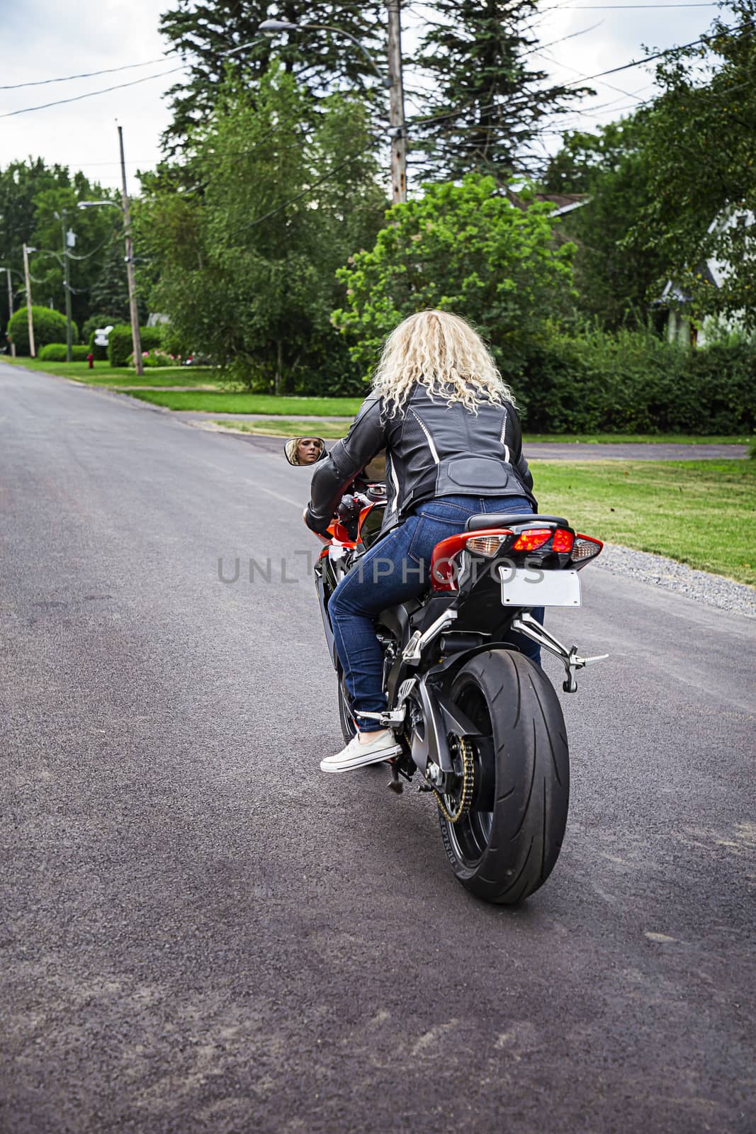 blond woman on a sport motocycle, driving aways