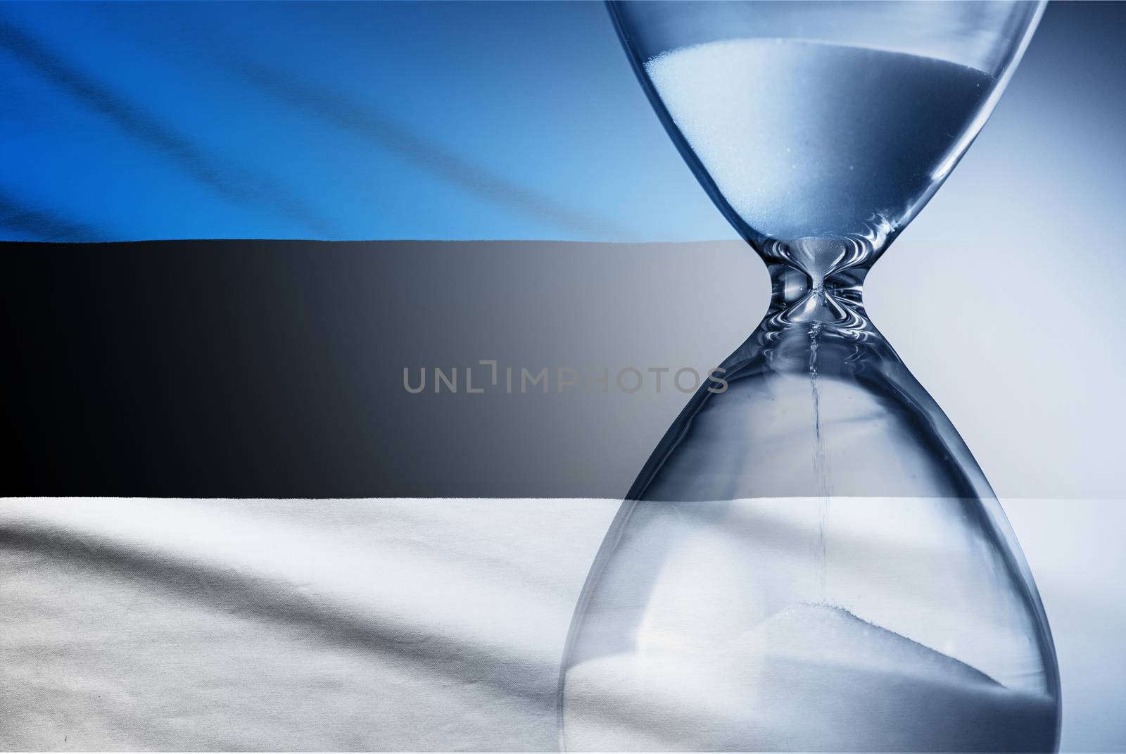 Flag of Estonia with superimposed hourglass with running sand conceptual of deadlines, countdown, passing time, urgency, crisis and time management