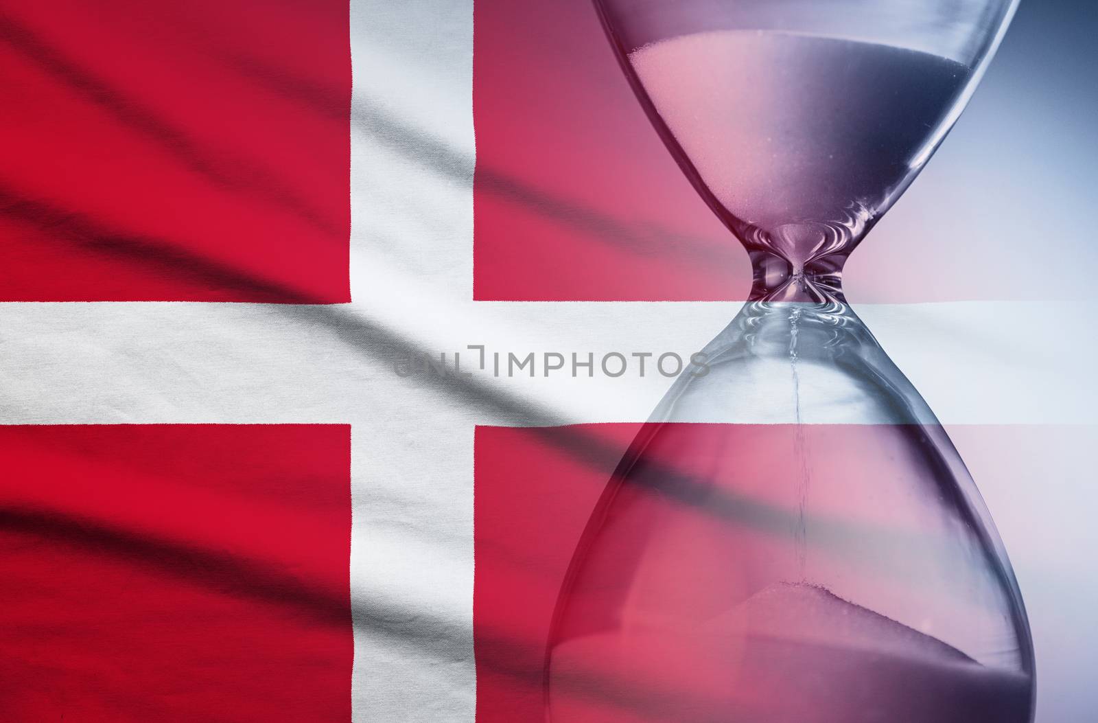Flag of Denmark with superimposed hourglass with running sand conceptual of deadlines, countdown, passing time, urgency, crisis and time management