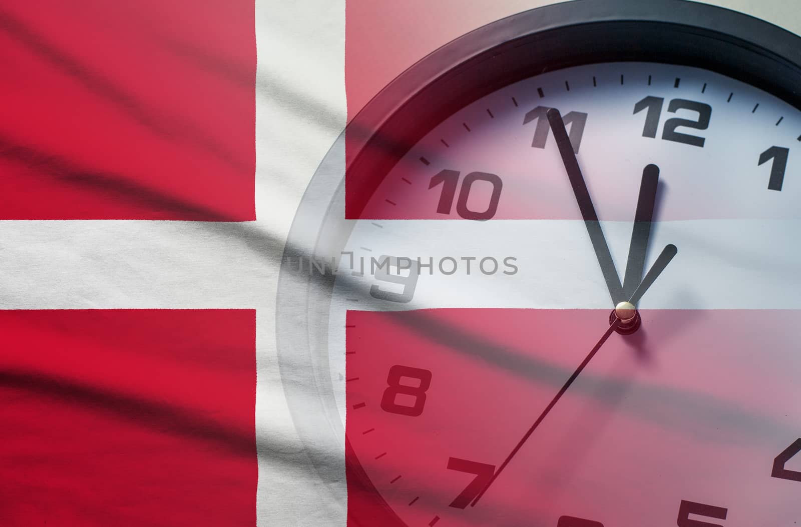 Denmark flag with dial of a clock counting down to twelve noon or midnight in a concept of crisis, deadlines or new year,