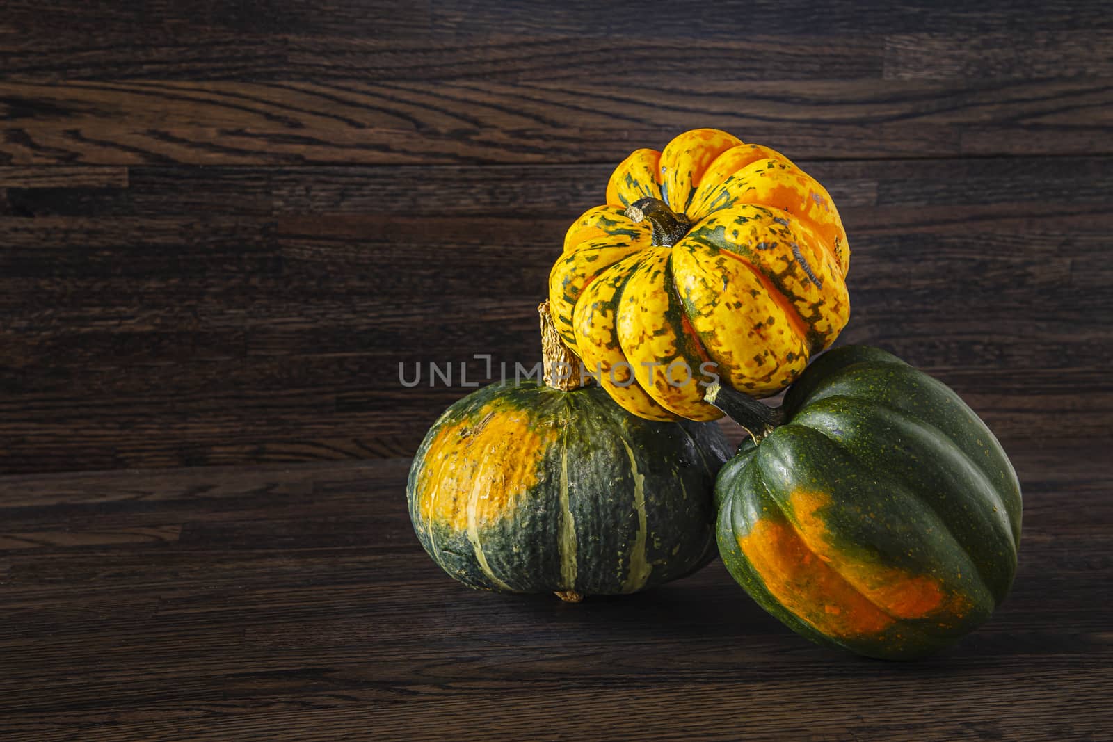 two Sweet Dumpling squash and one Kabocha squash in a stack against a wood background