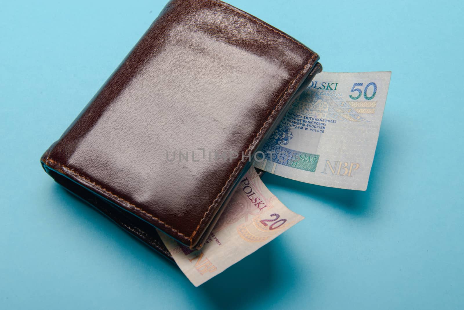 brown mans leather wallet with money bills on a blue background