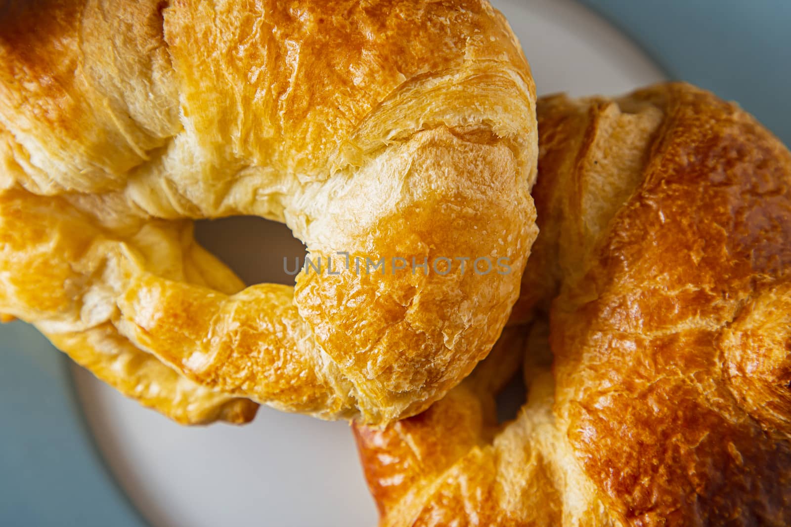 close up top view of two croissant on a blue rimmed plate