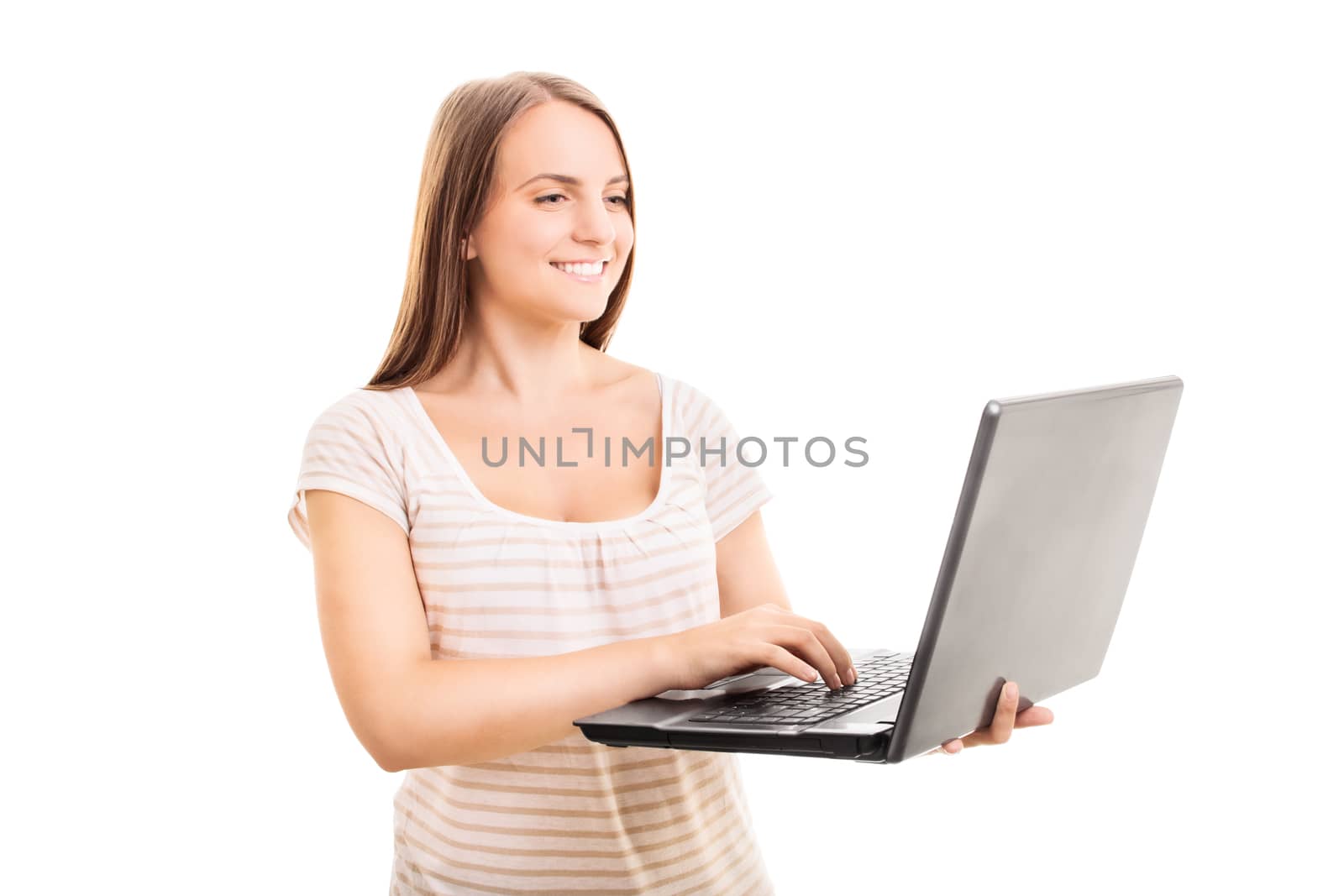 Portrait of a beautiful smiling young woman in casual clothes holding a laptop computer and typing with one hand, isolated on a white background. Technology concept.