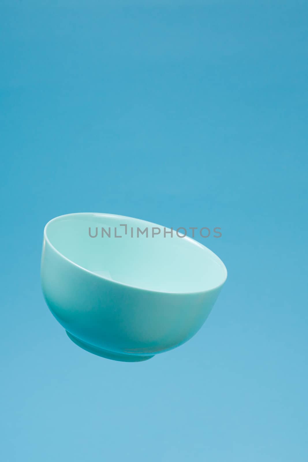 A blue ceramic mattle deep bowl for breakfast flying on blue bac by alexsdriver