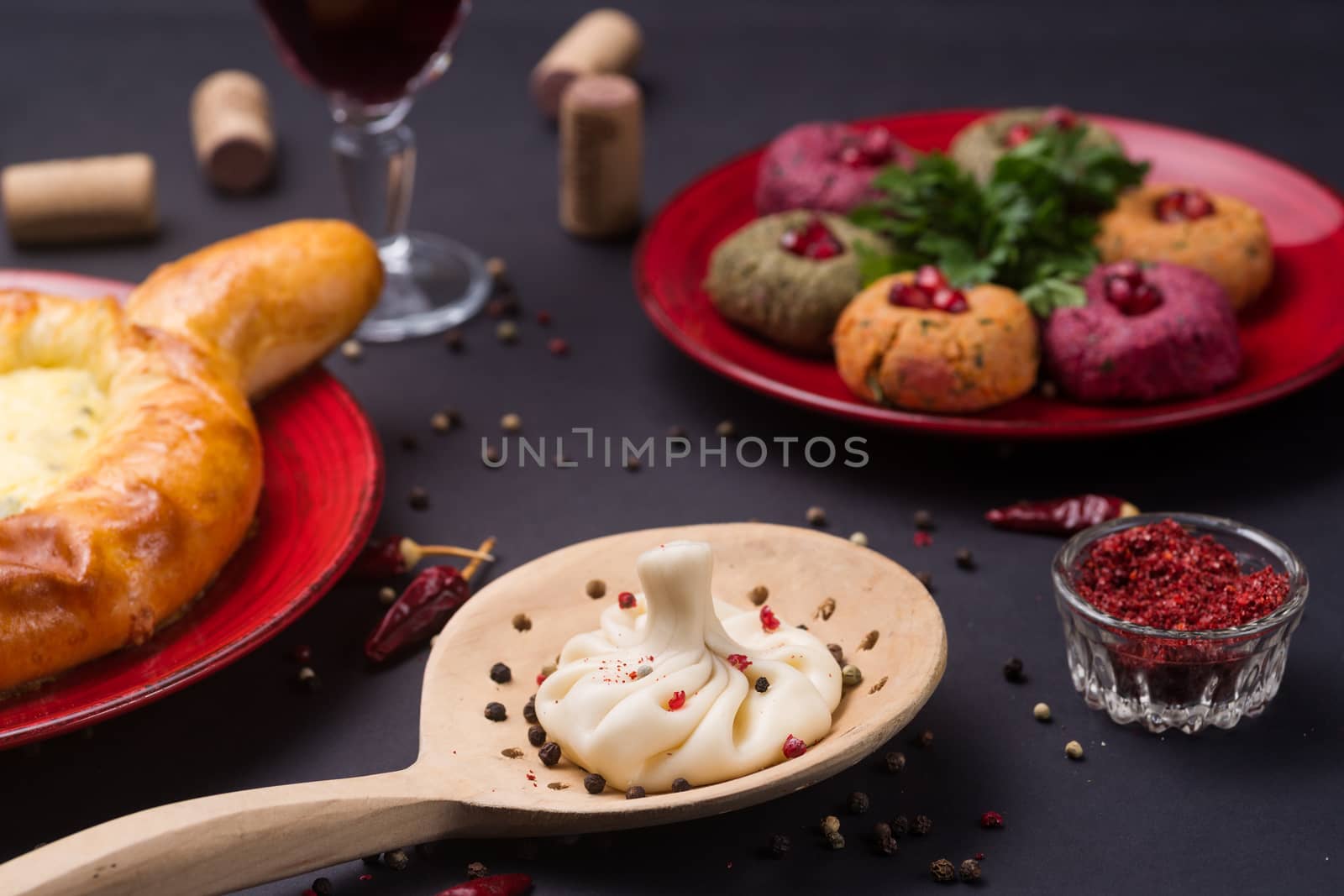 Georgian food on black table. khinkali, phali,  khachapuri with tomatos, adjika and a glass of wine.