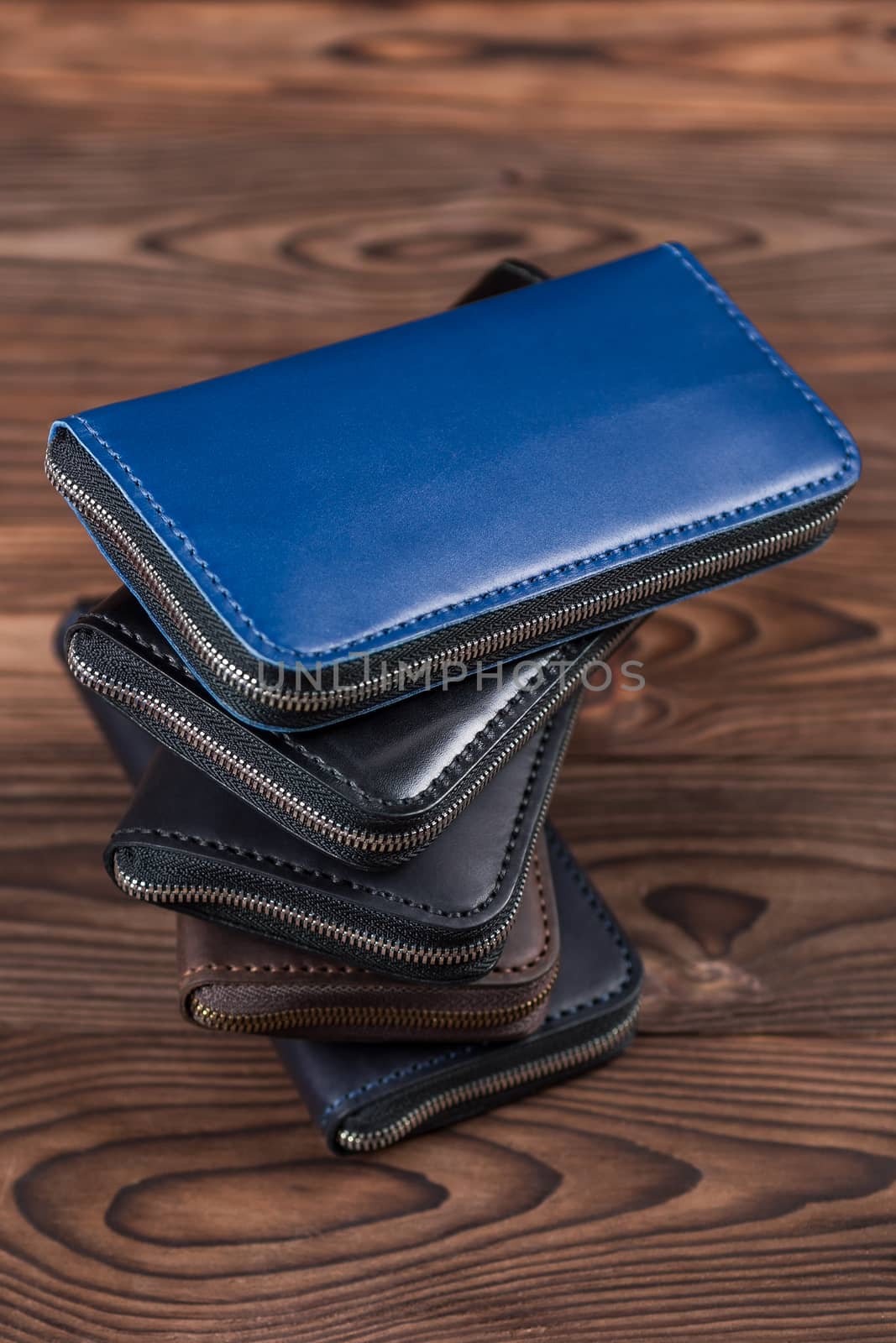 A stack of handmade leather wallets on wooden blurred background