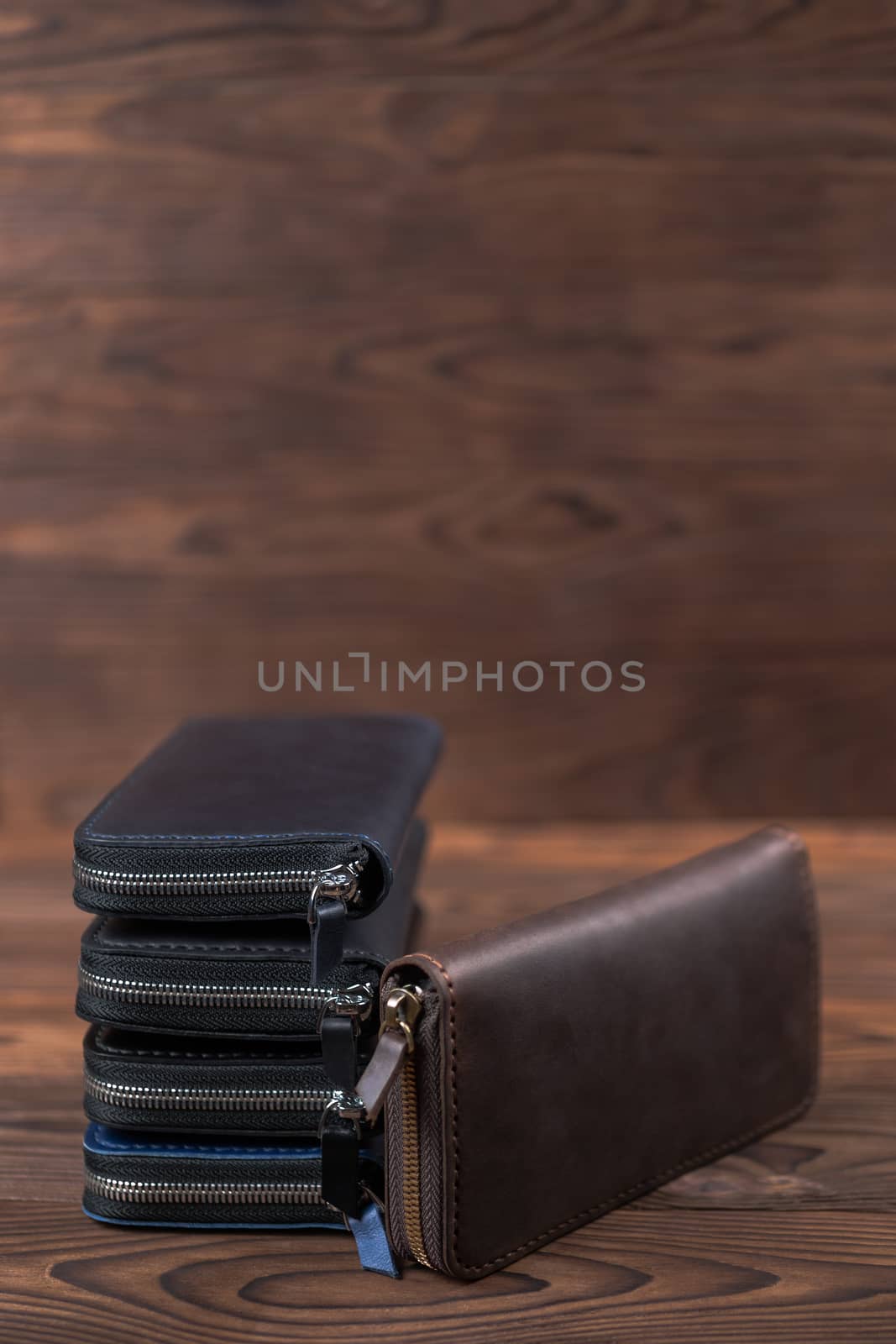 A stack of handmade leather wallets on wooden blurred background