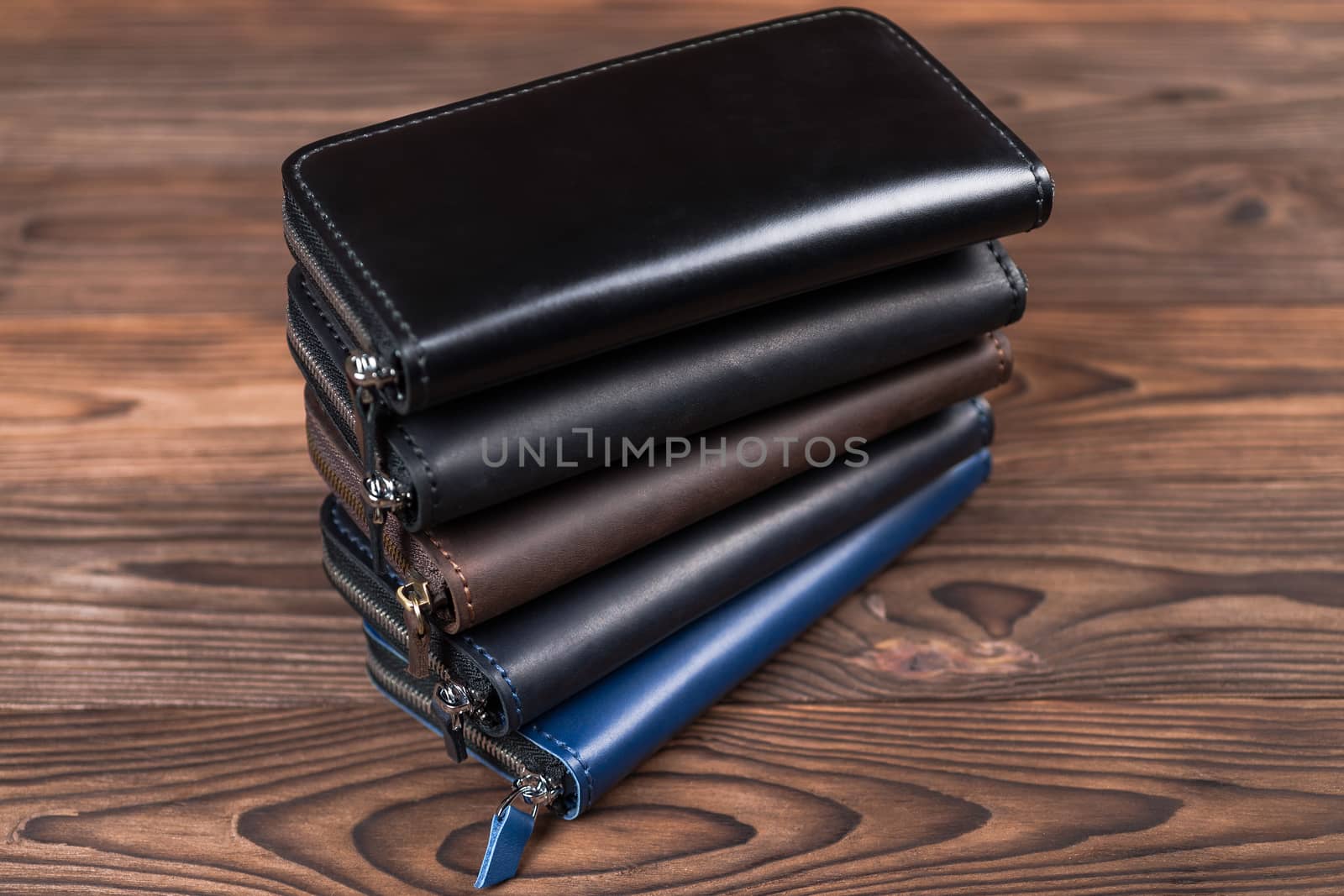 A stack of handmade leather wallets on wooden background