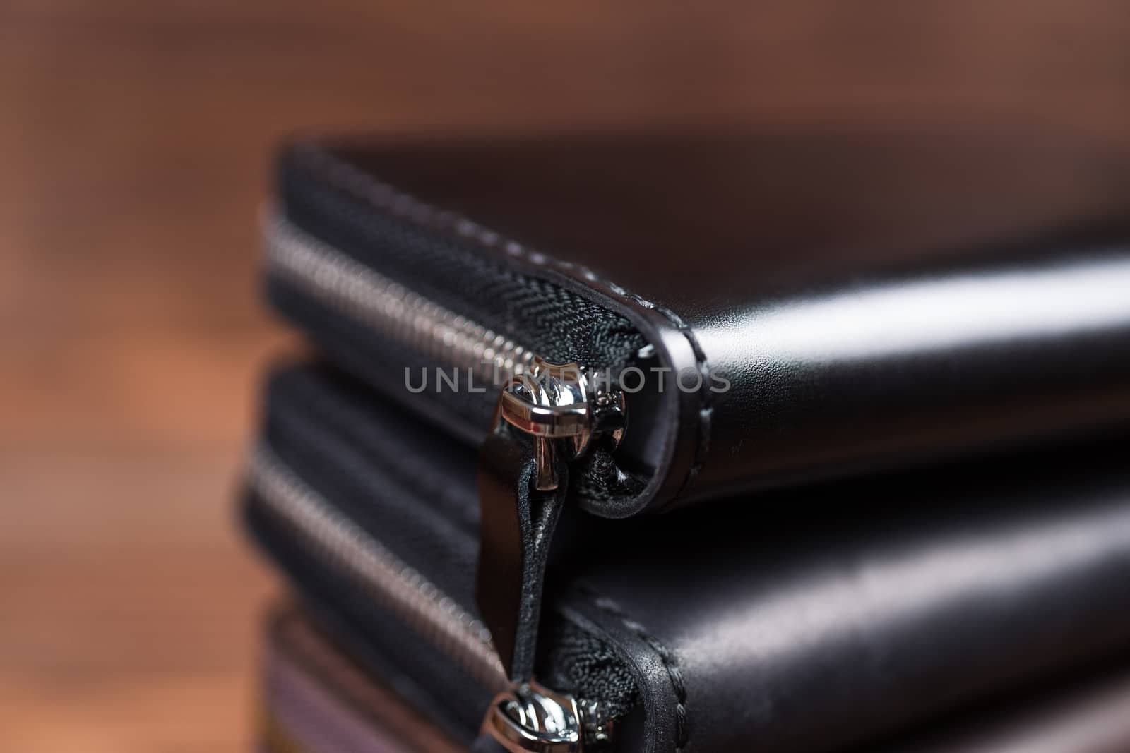 A stack of handmade leather wallets on wooden blurred background. Close up view.