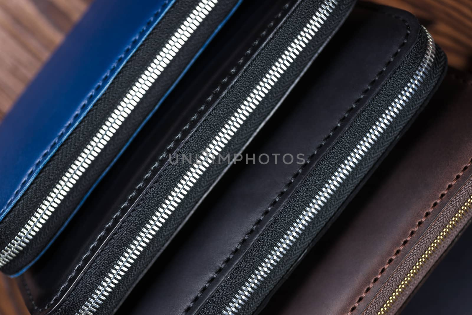 A stack of handmade leather wallets on wooden blurred background. Close up view.