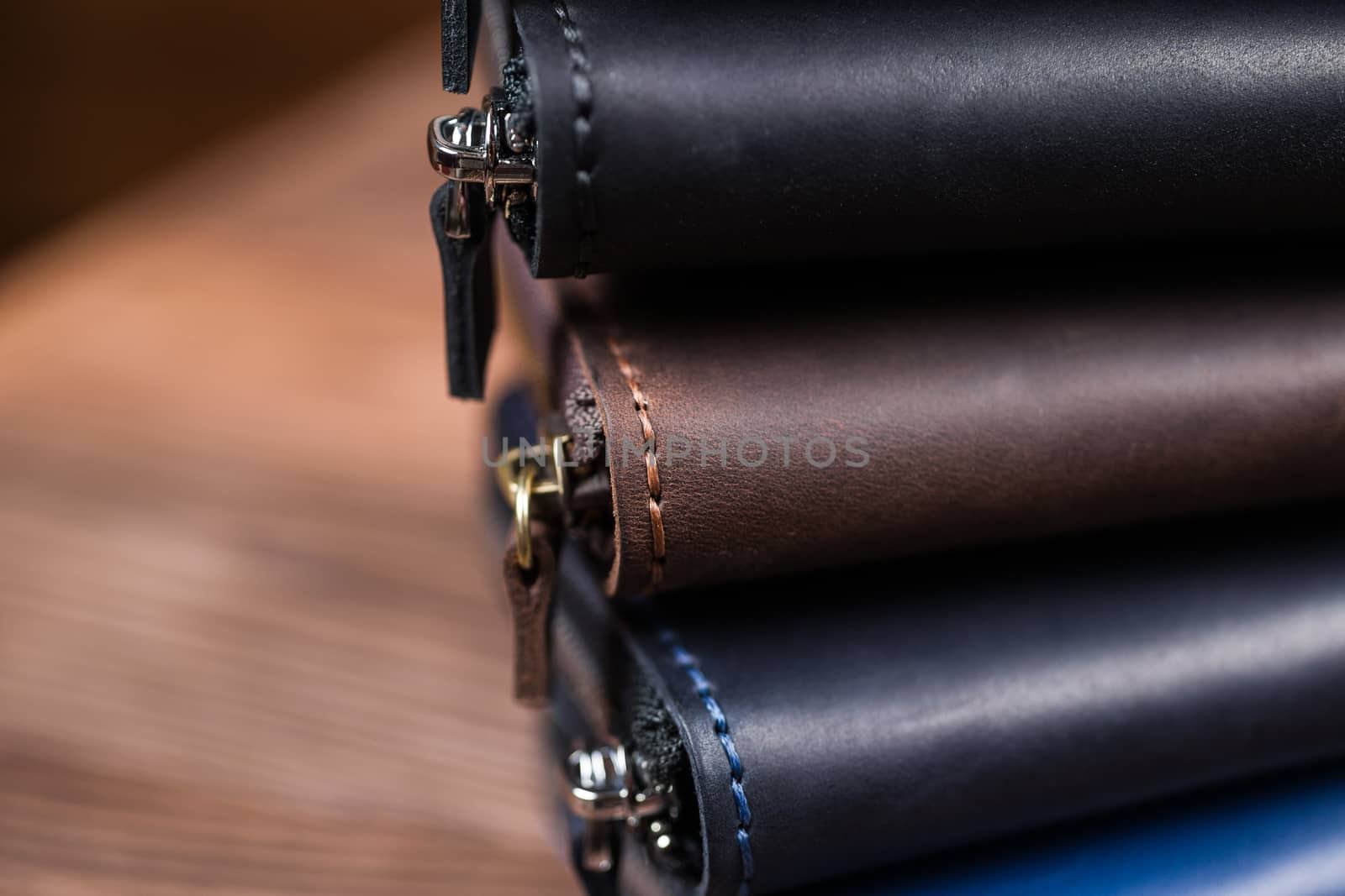 A stack of handmade leather wallets on wooden blurred background. Close up view.