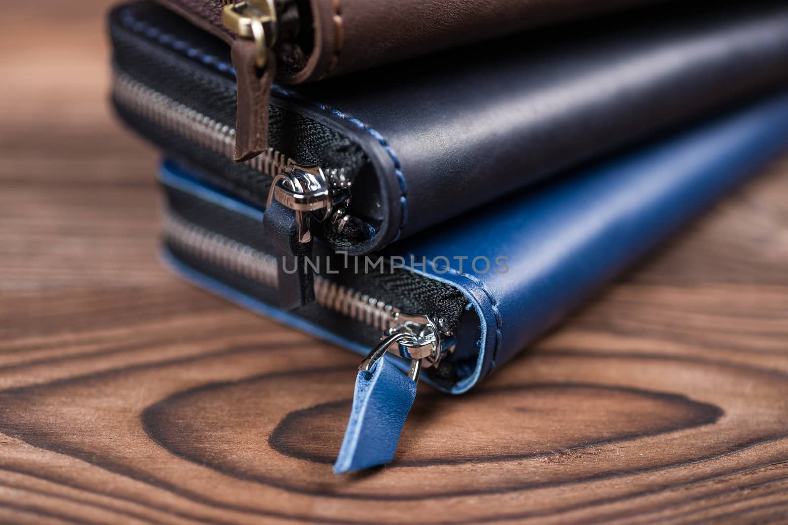 A stack of handmade leather wallets on wooden blurred background. Close up view.