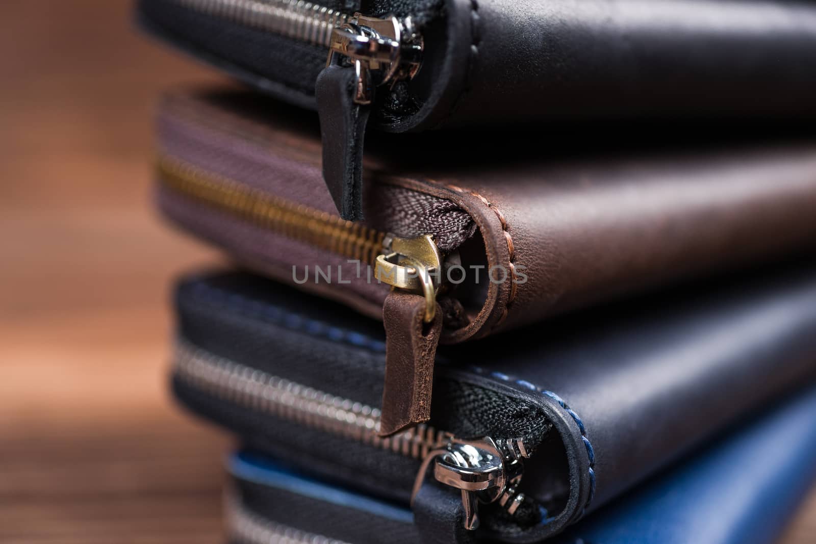 A stack of handmade leather wallets on wooden blurred background. Close up view.