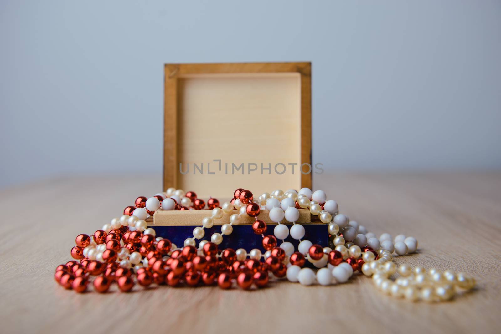 Gift box and red beads necklace on wooden background by Brejeq