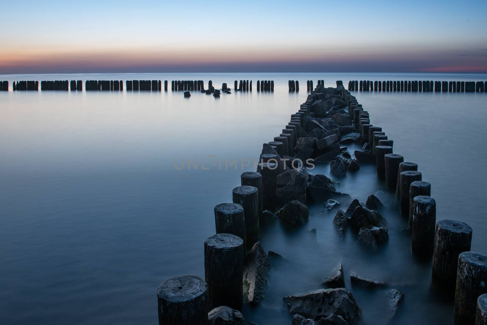 Wooden breakwater at sunset on the Baltic Sea by Brejeq
